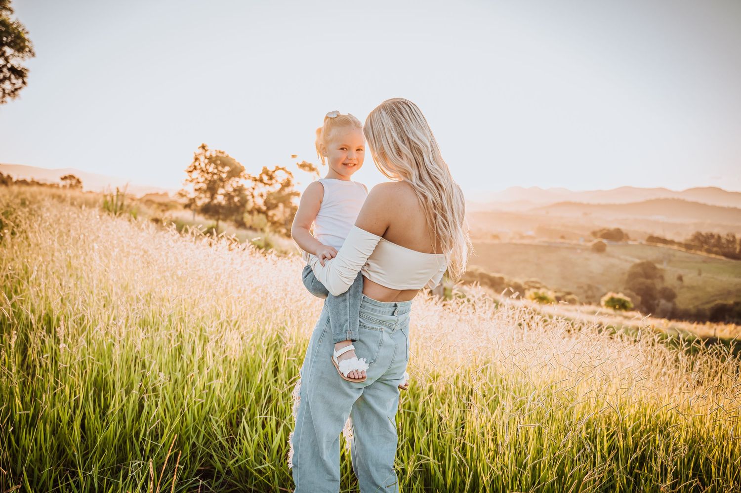 Sweet embrace captured during golden hour in rolling hills covered with tall grass.