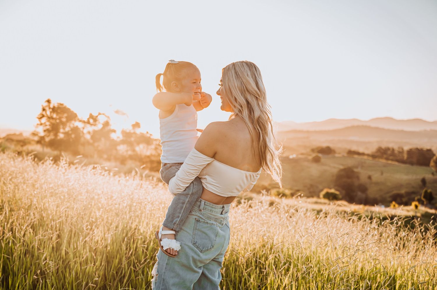 Joyful playtime moment in a sun-lit meadow with lifting and spinning.