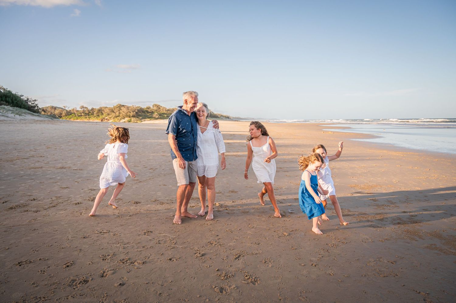 Joyful family moment captured on the beach with people running and playing in the sand.