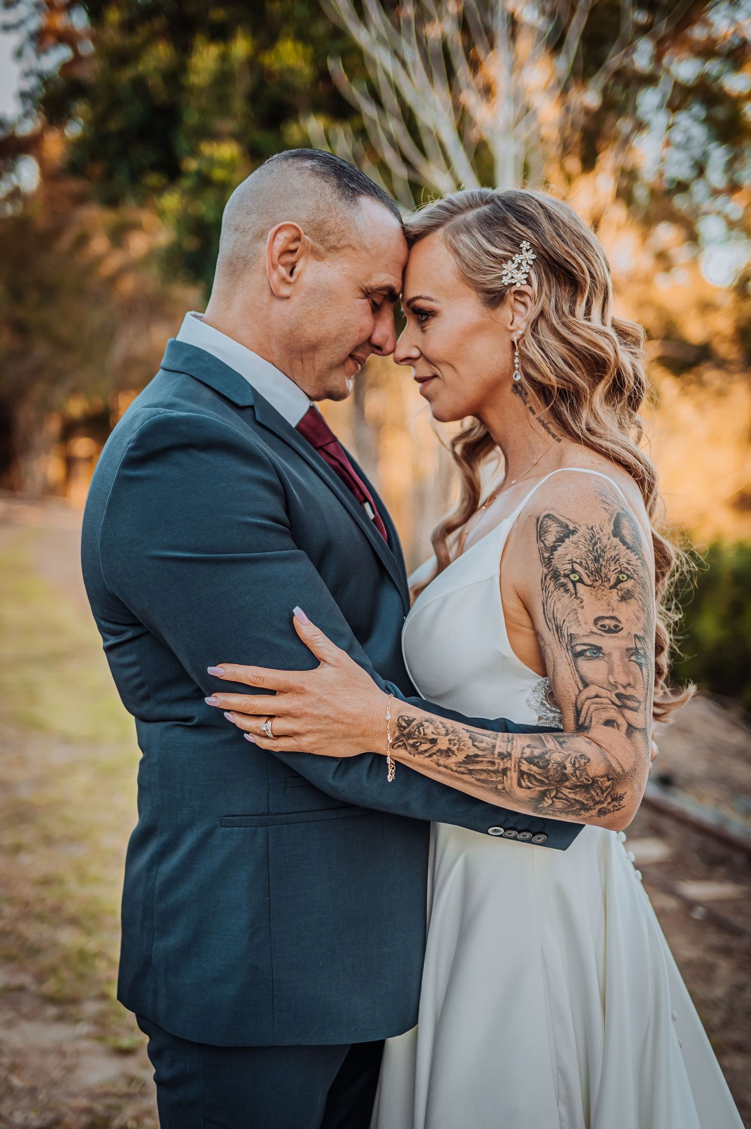Intimate wedding portrait showing couple in formal attire sharing tender moment at sunset.