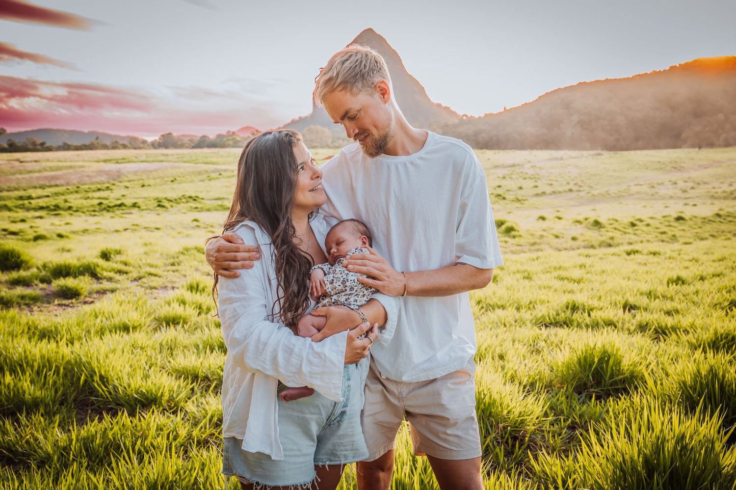 Family sharing intimate moment together in golden grass field at sunset.