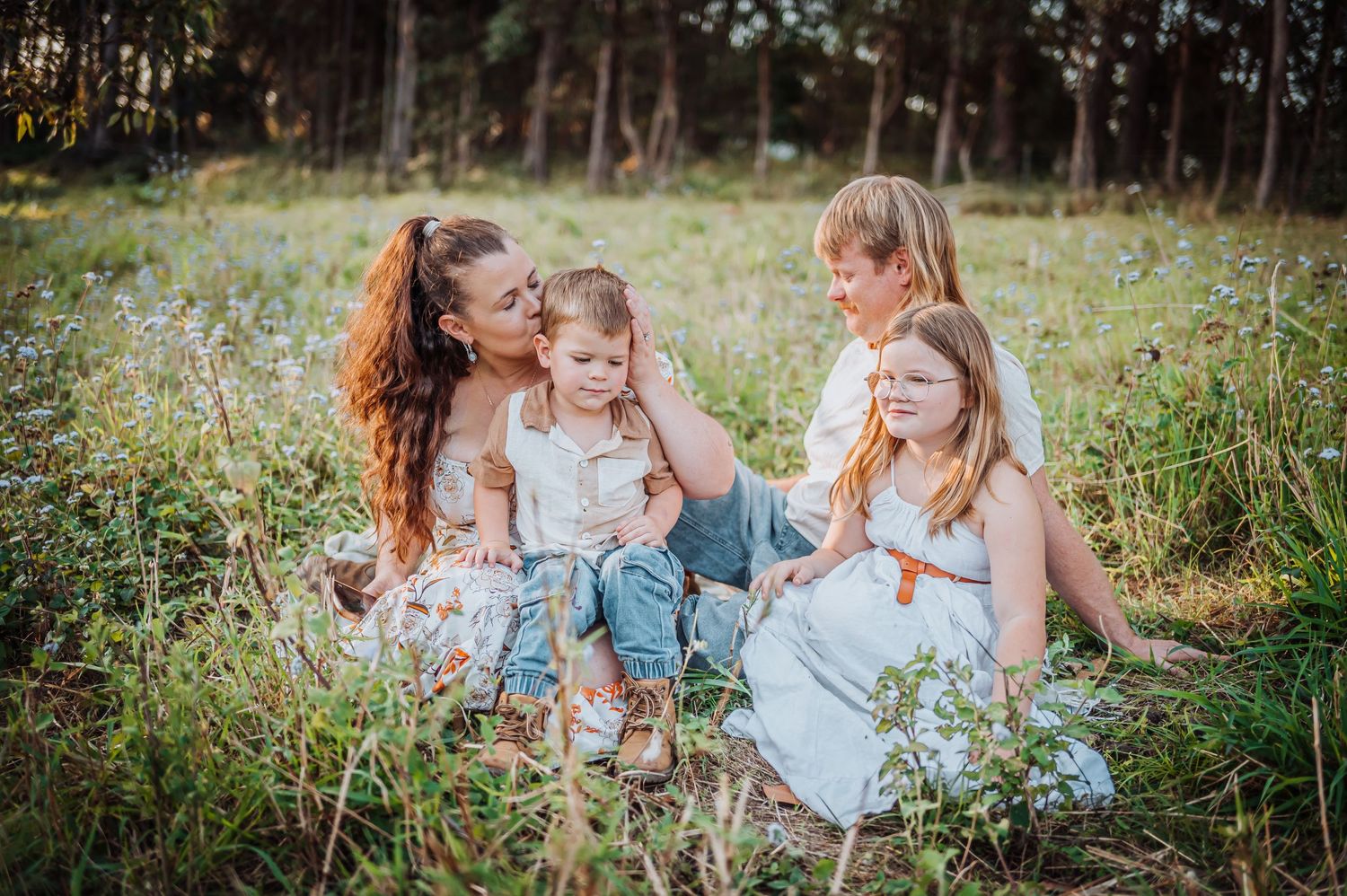 Family sitting together in a wildflower meadow during golden hour.