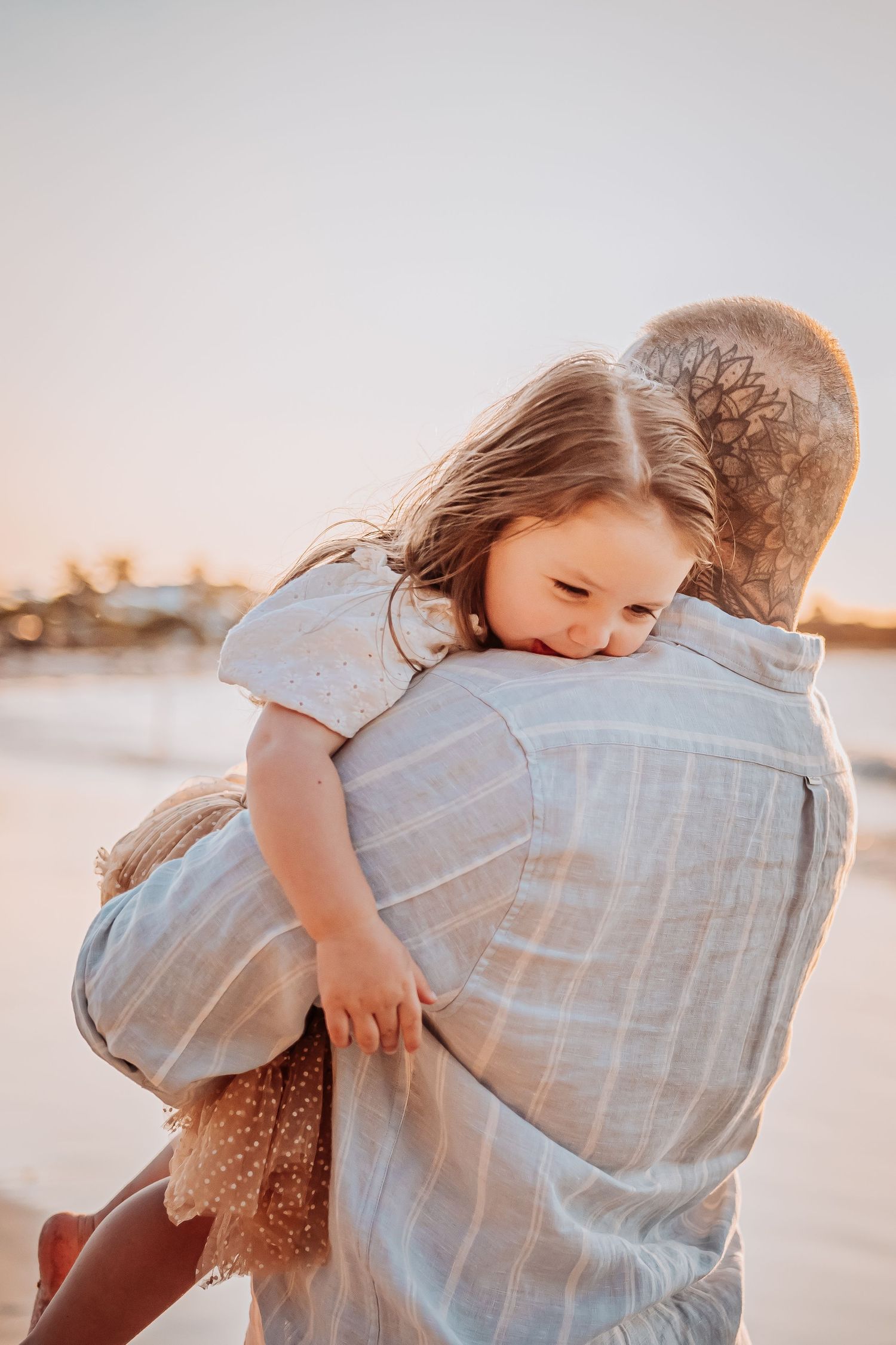 Tender embrace captured on beach during golden hour sunset.