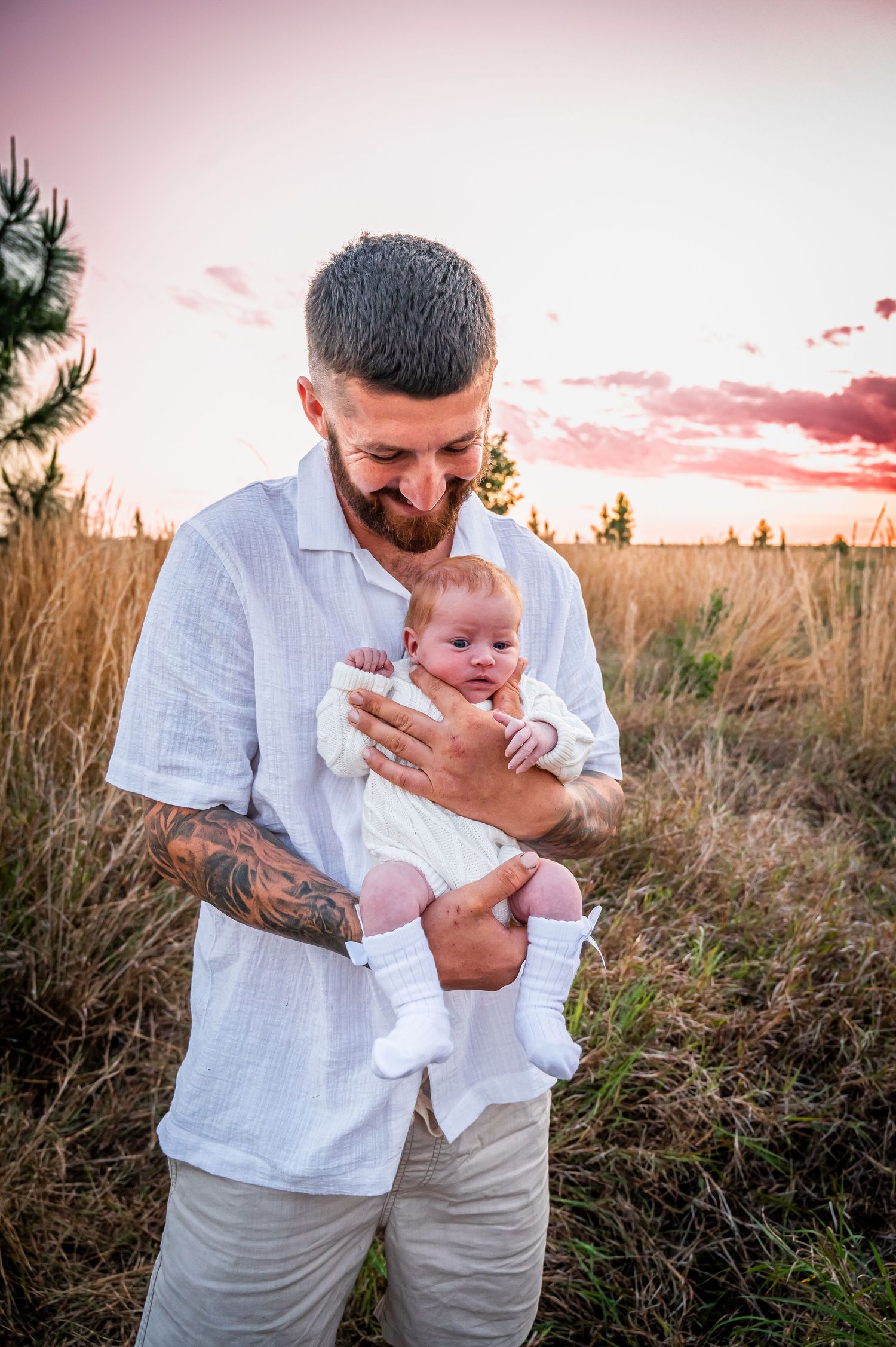 An intimate moment between parent and newborn baby outdoors during sunset.