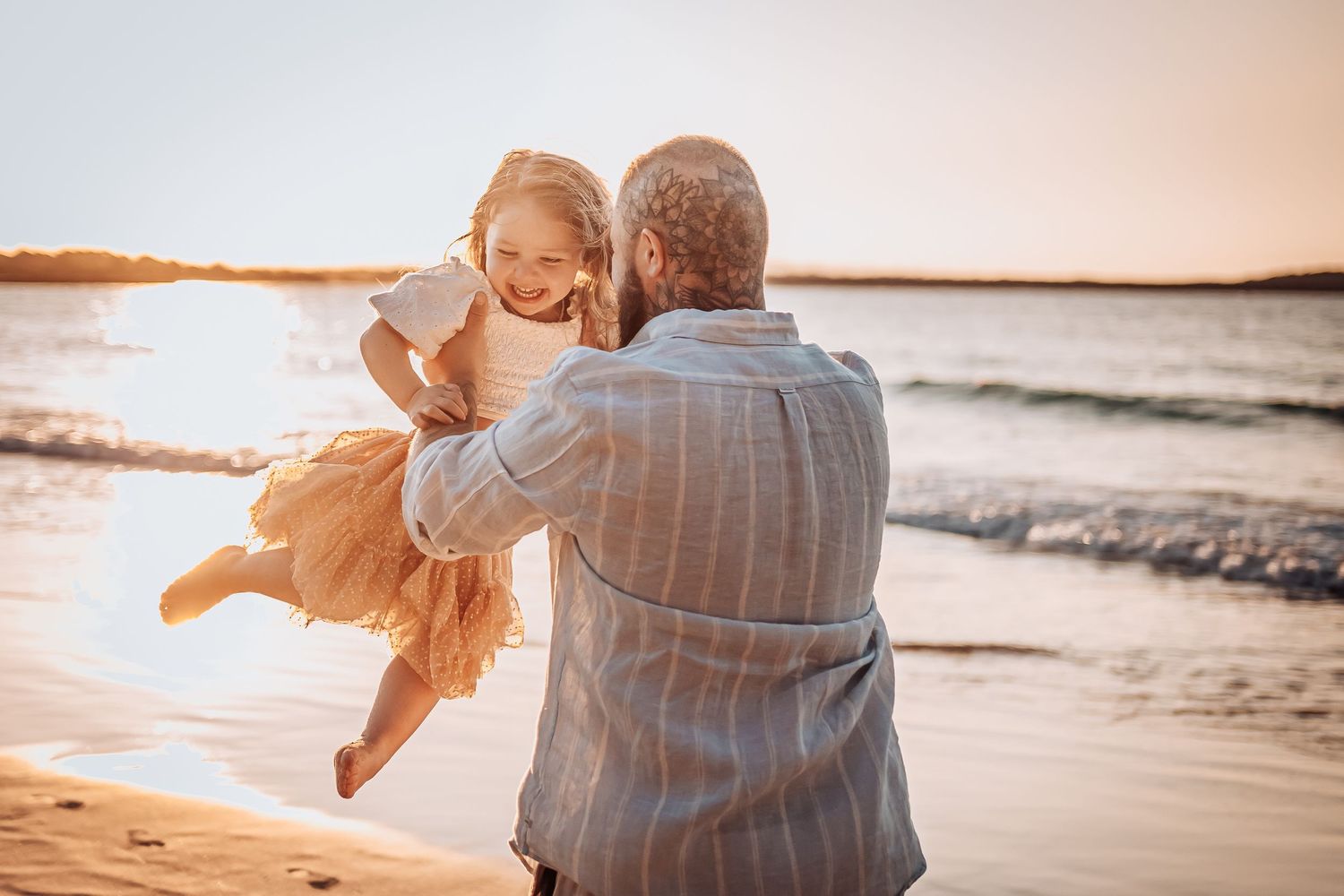Joyful playtime on beach at sunset with waves and shoreline in background.
