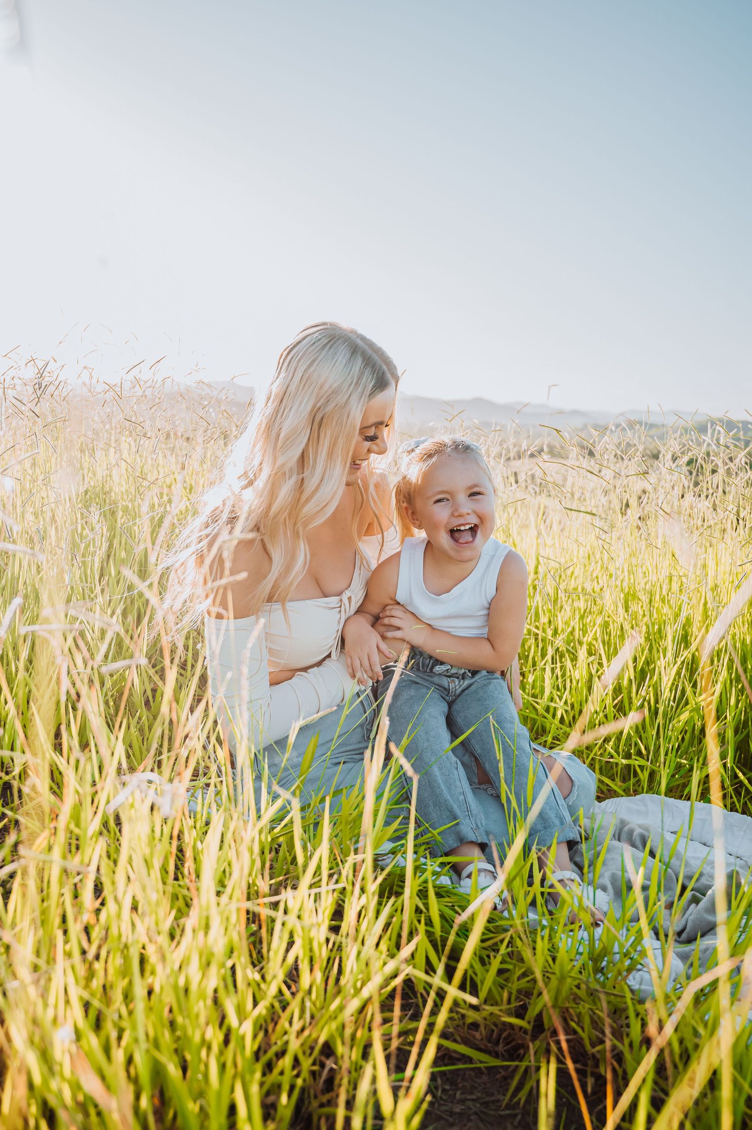 Candid moment of laughter in tall summer grass during golden hour sunlight.