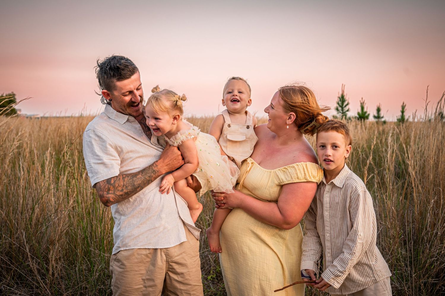 Happy family sharing joyful moment together in field at sunset.