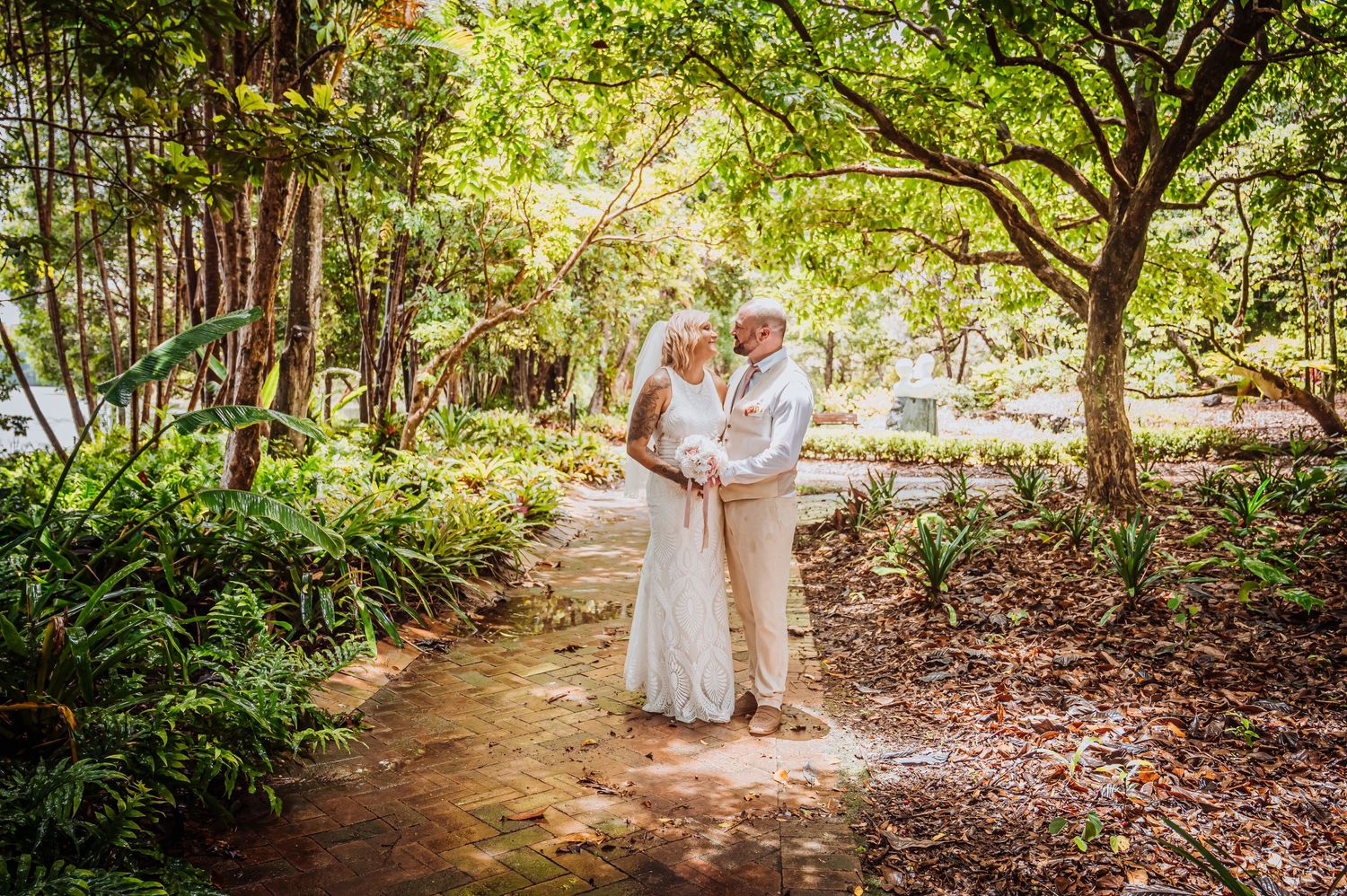 Garden wedding portrait on winding path surrounded by tropical foliage and trees.