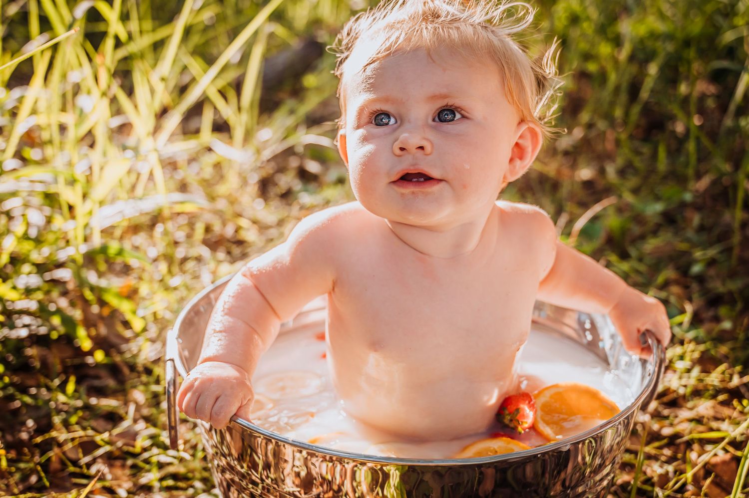 Whimsical outdoor milk bath setup with floating citrus slices and flowers.