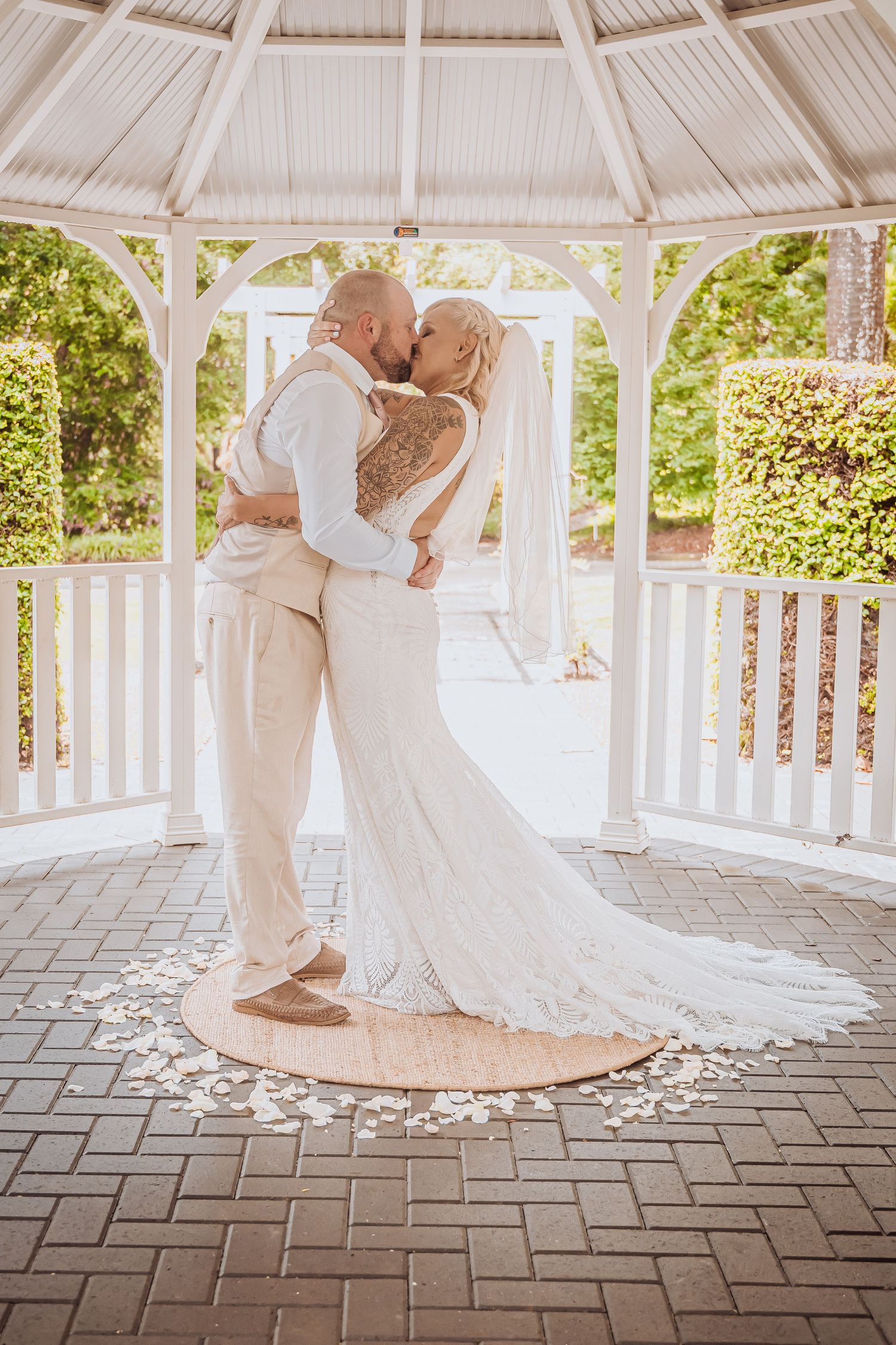 Romantic kiss shared between newlyweds in a decorative garden gazebo.