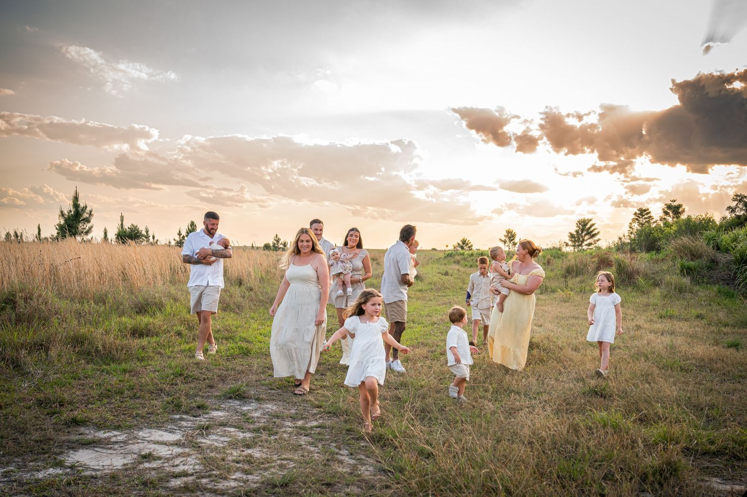 Group in white clothing running through meadow at sunset.