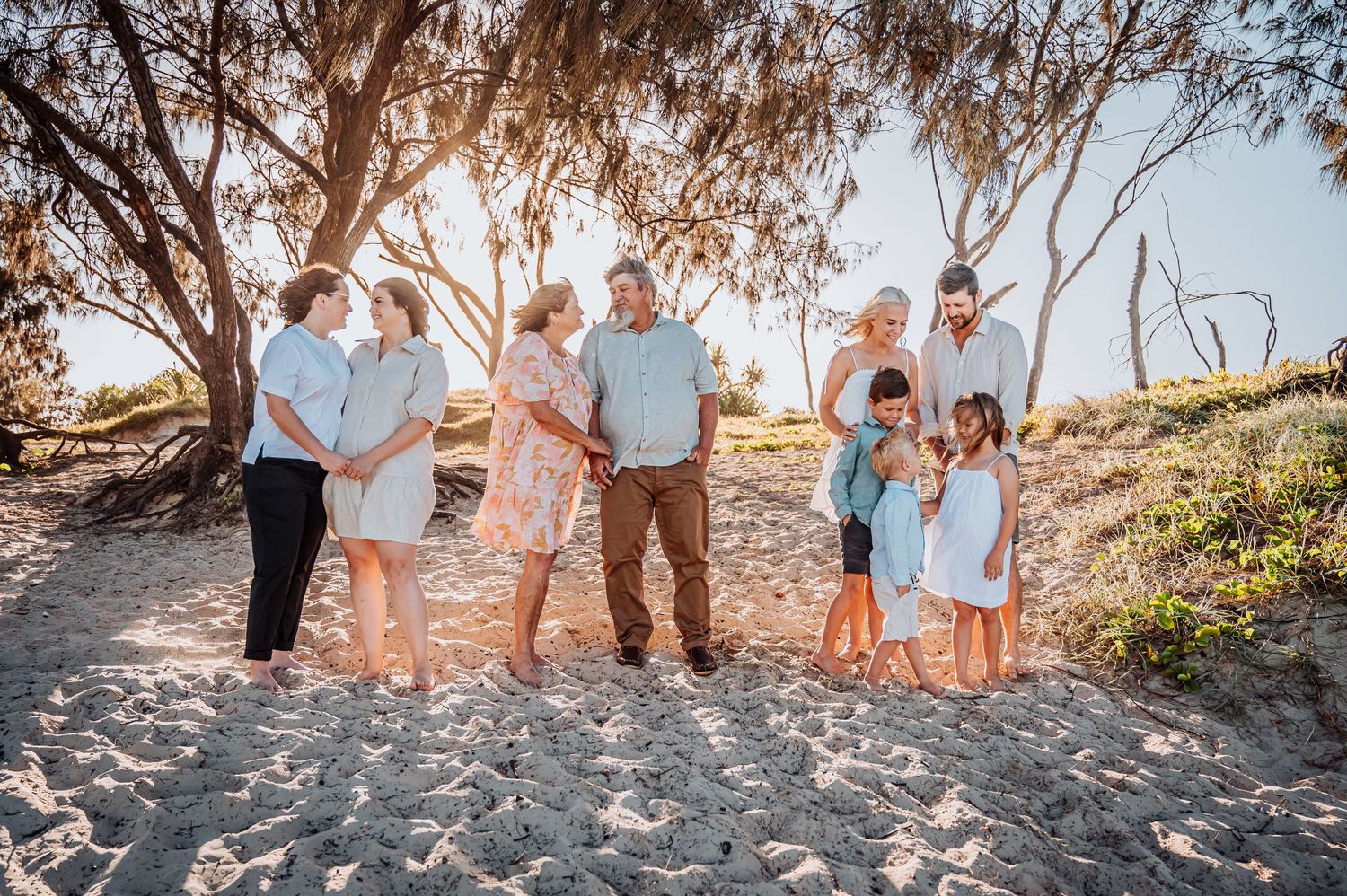 Extended family group gathered together on a beach path during golden hour.