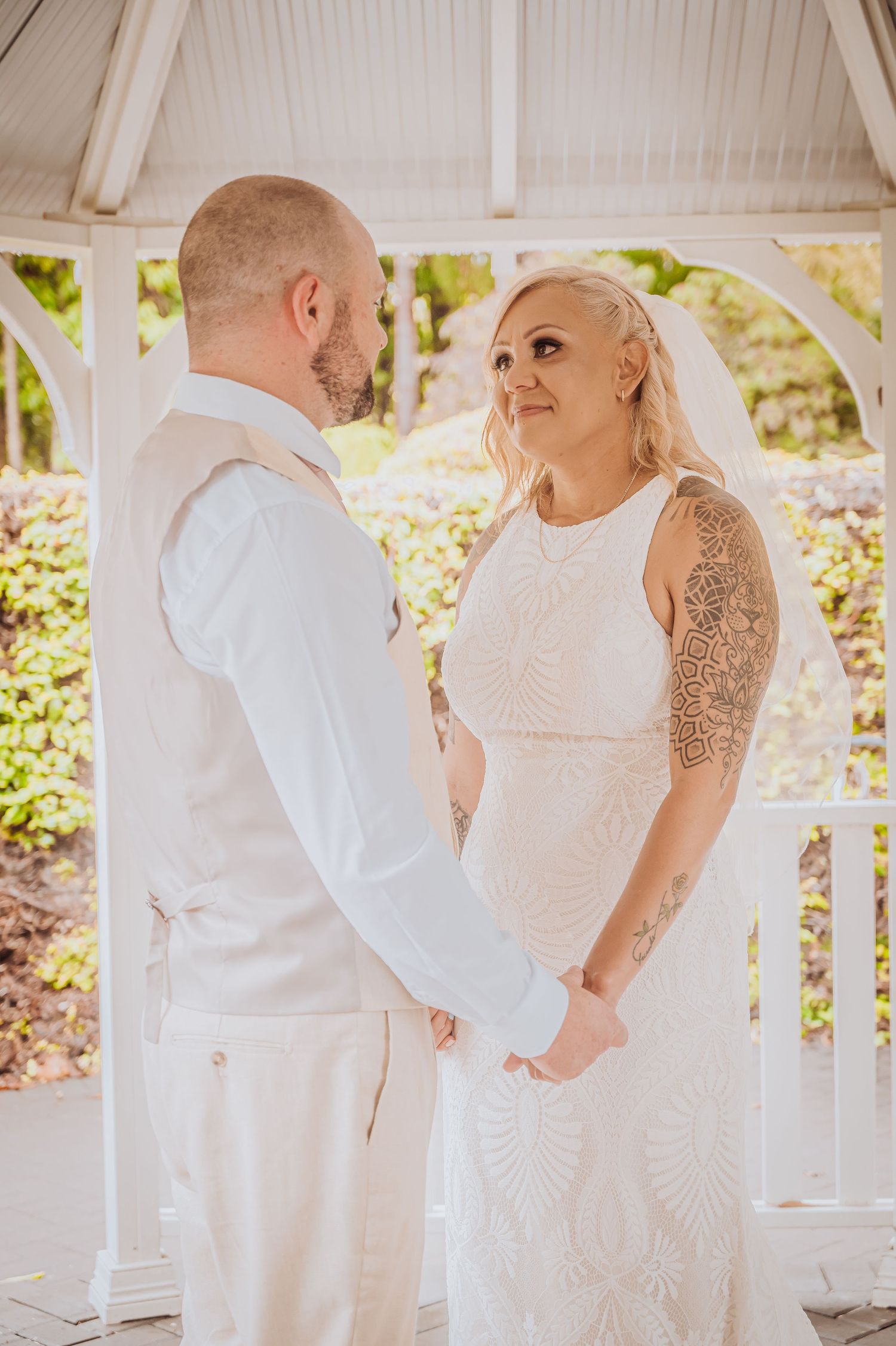 Couple sharing a tender moment during their wedding ceremony in a white garden gazebo.