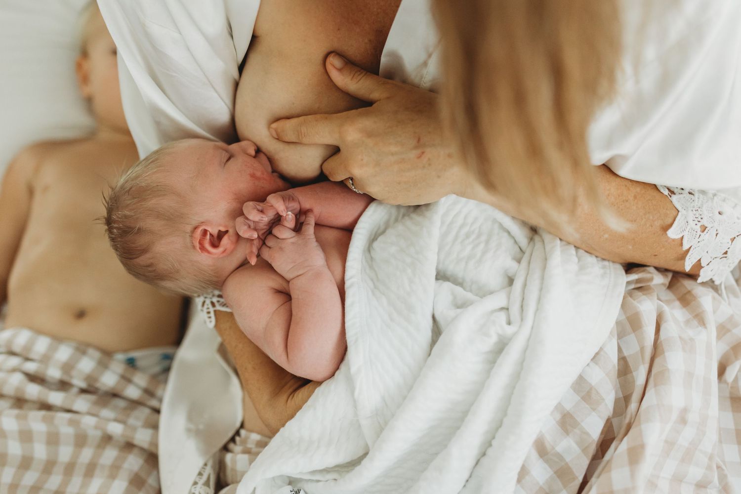 Newborn baby wrapped in muslin blanket being held by mother during fresh 48 session.