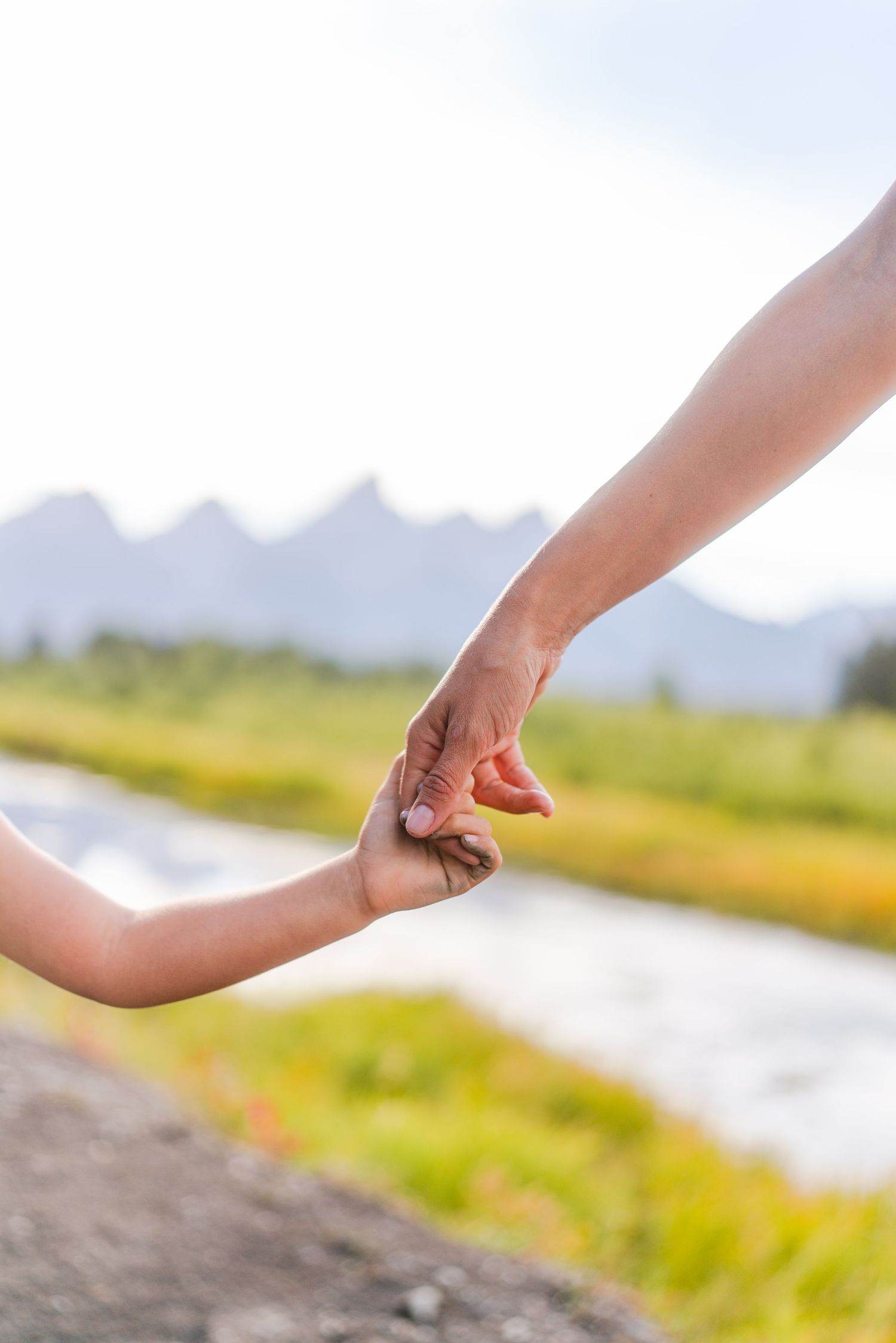 Mom and Daughter holding hands with the Tetons in the background