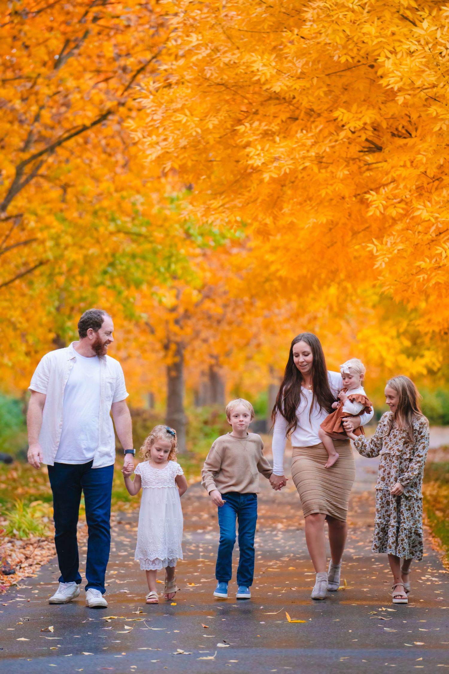 Family walking down path with fall leaves behind them.