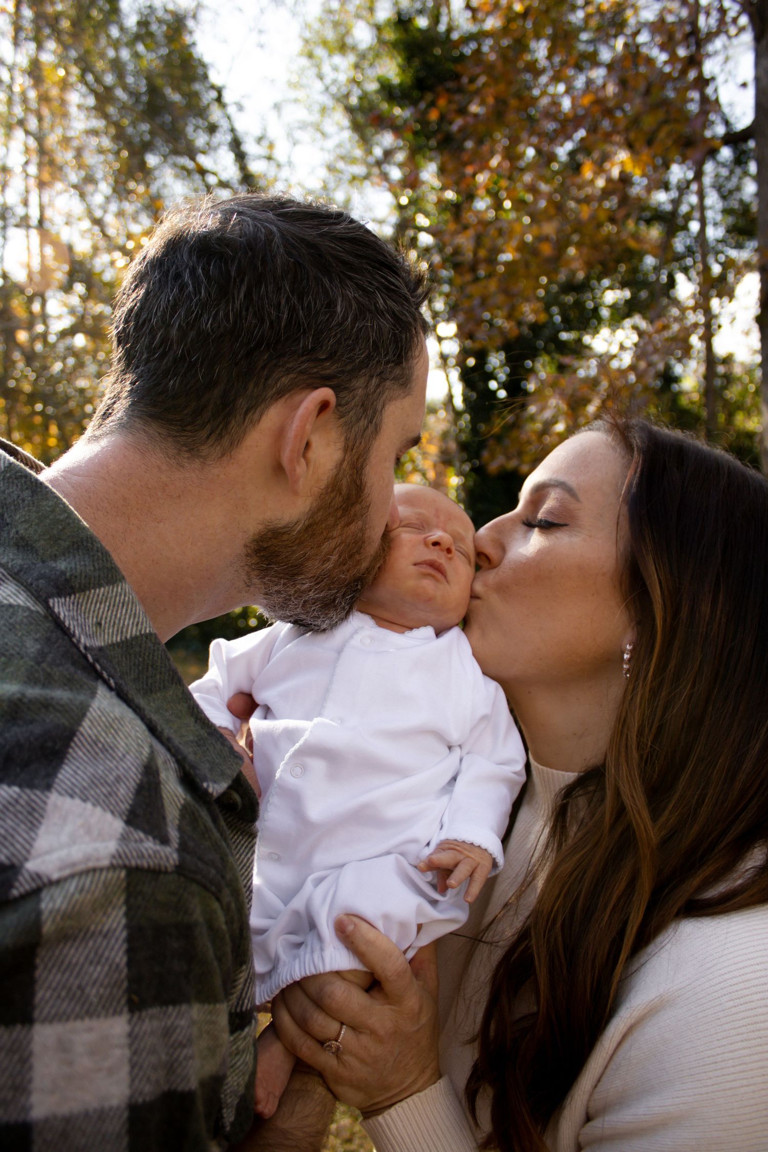 family, mom and dad holding baby, mom and dad kissing baby on both cheeks