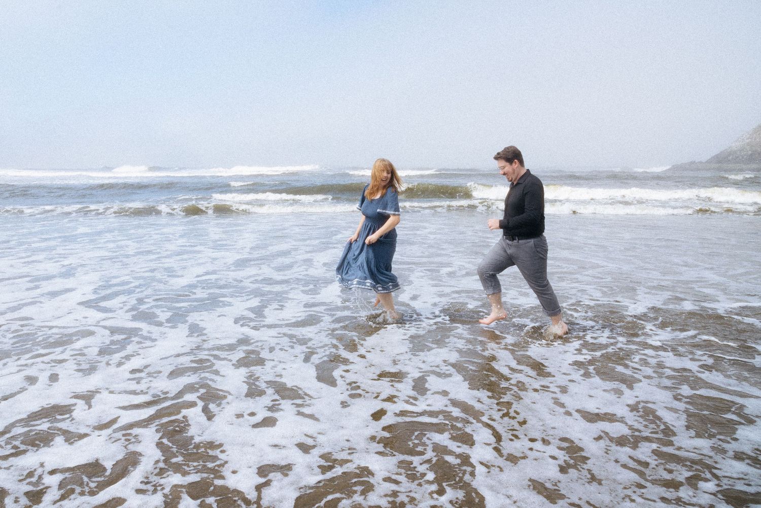 Candid film style photo of a couple running in the water at the Oregon coast