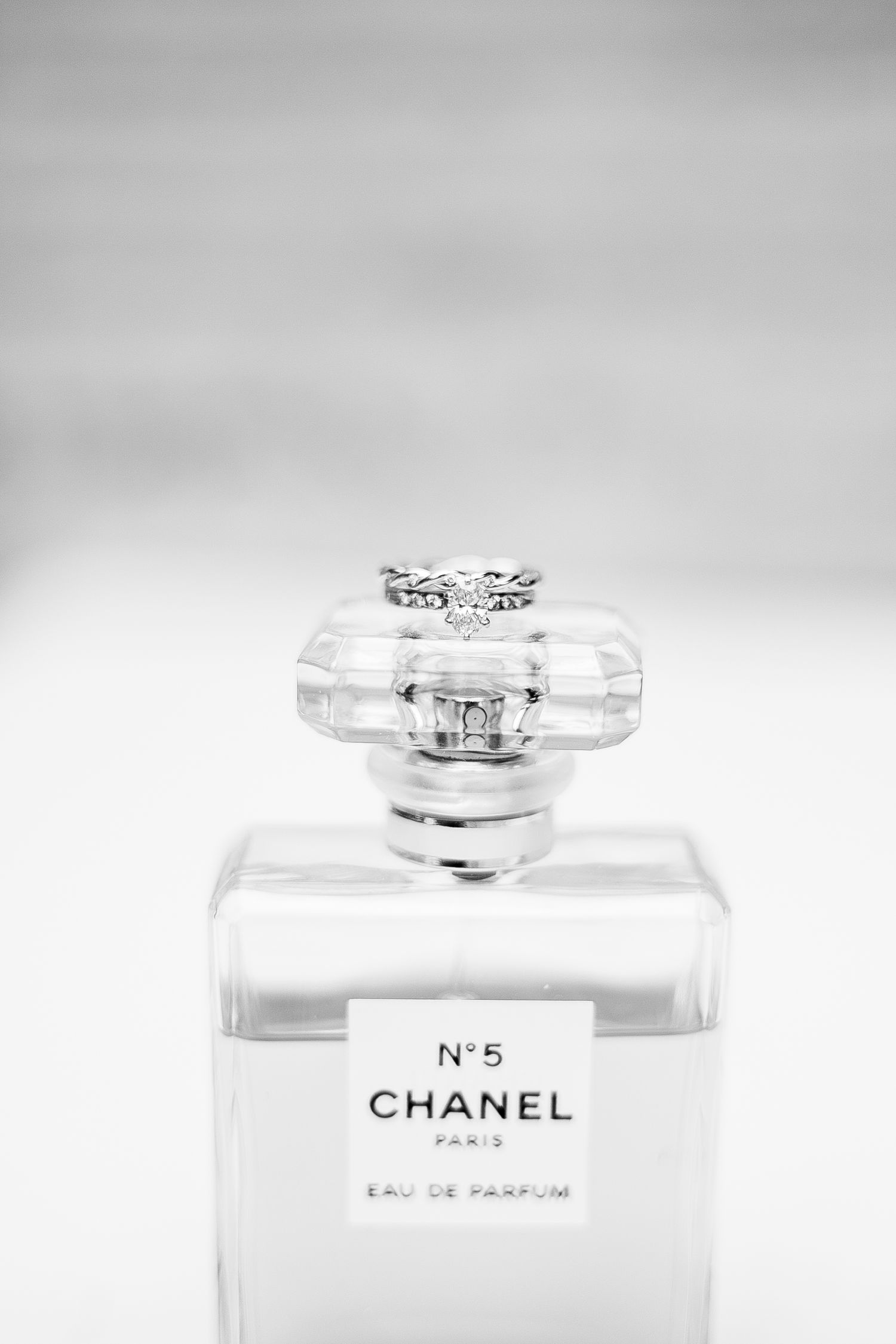 Minimalist black and white composition showing Chanel No 5 perfume bottles arranged in gradient sequence against white backdrop.