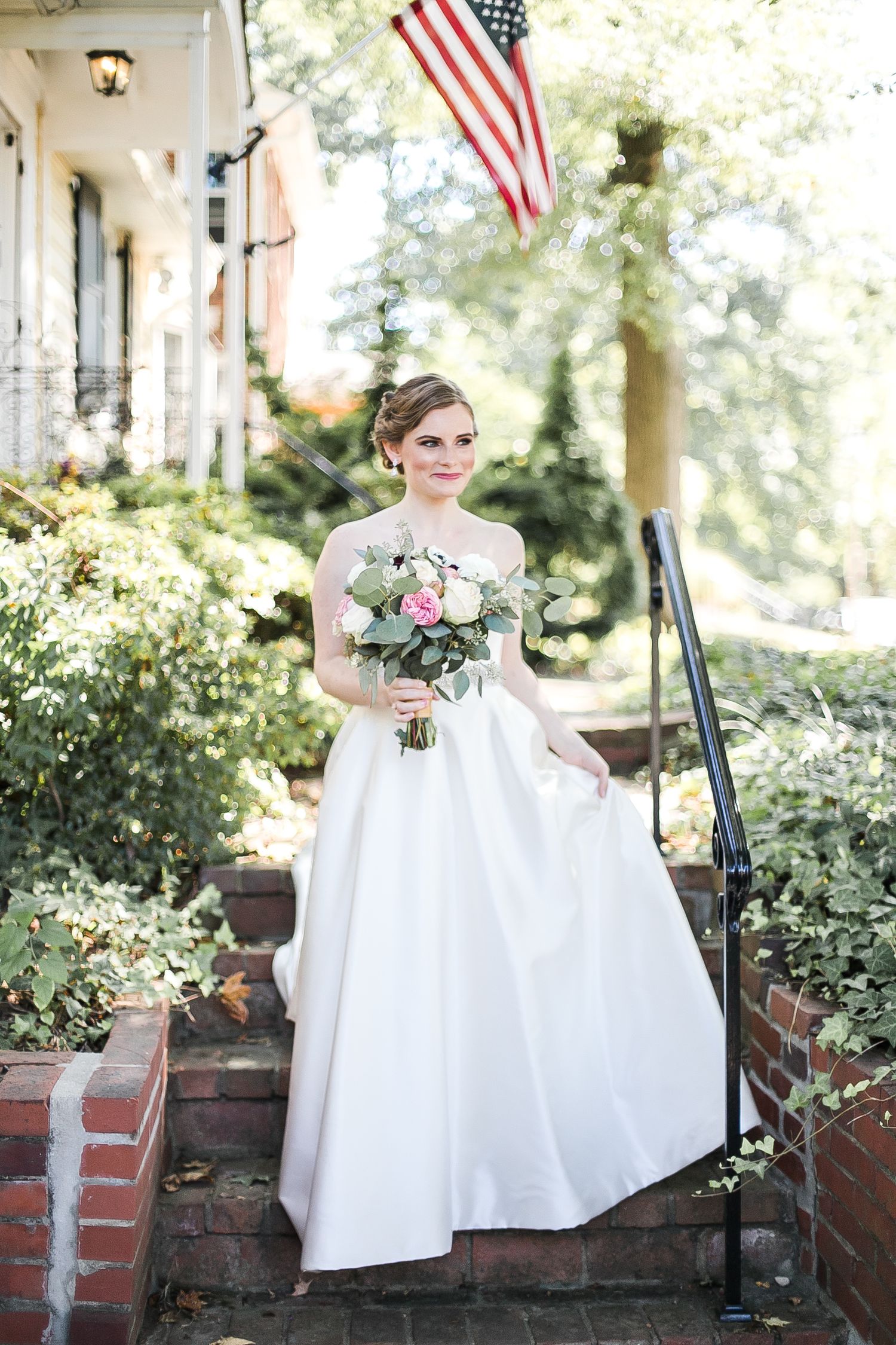 Four sequential images of a bride in a white dress sitting on brick steps with American flags flying in the background.