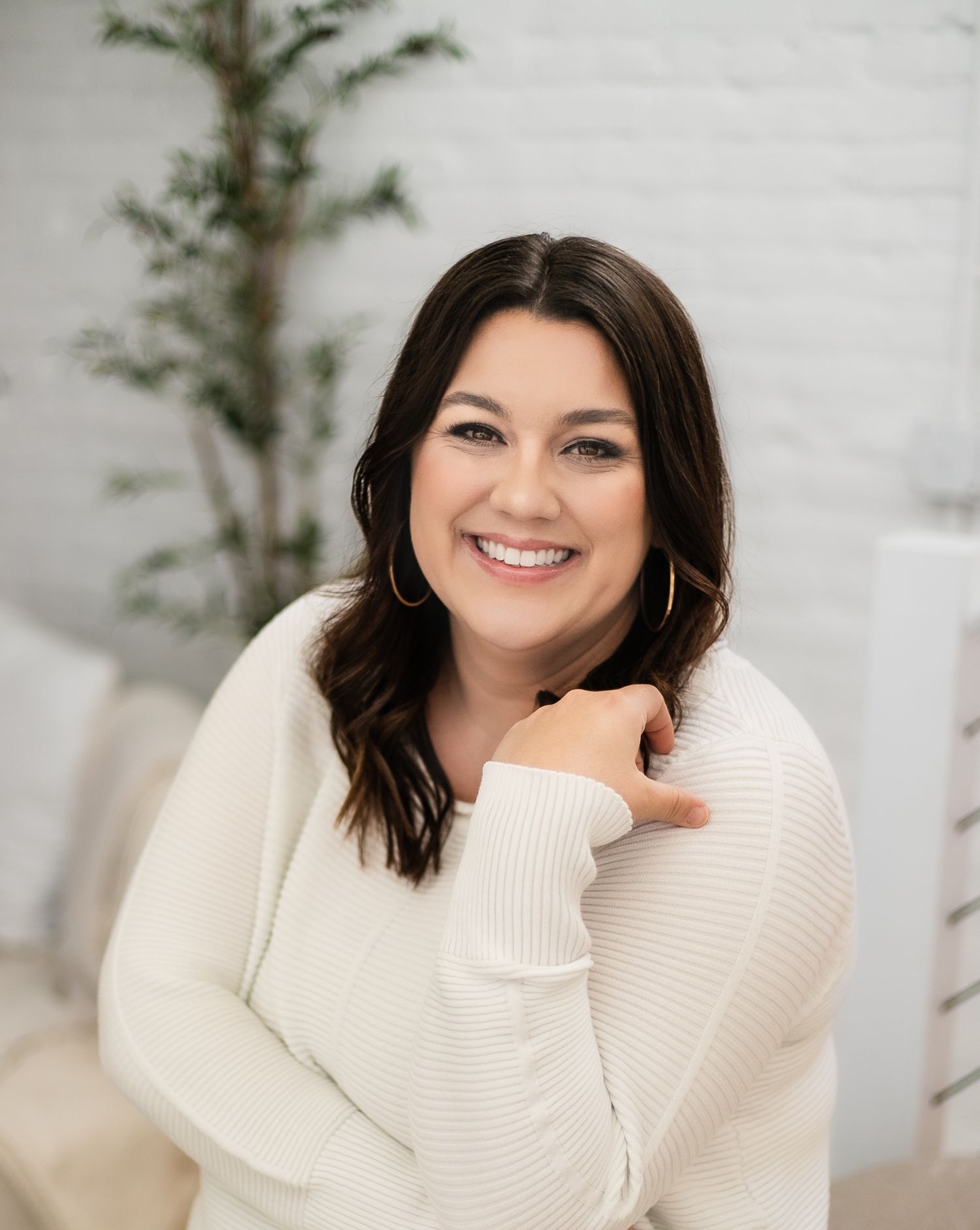 A woman wearing a white sweater poses with a natural smile in a winter photography session.