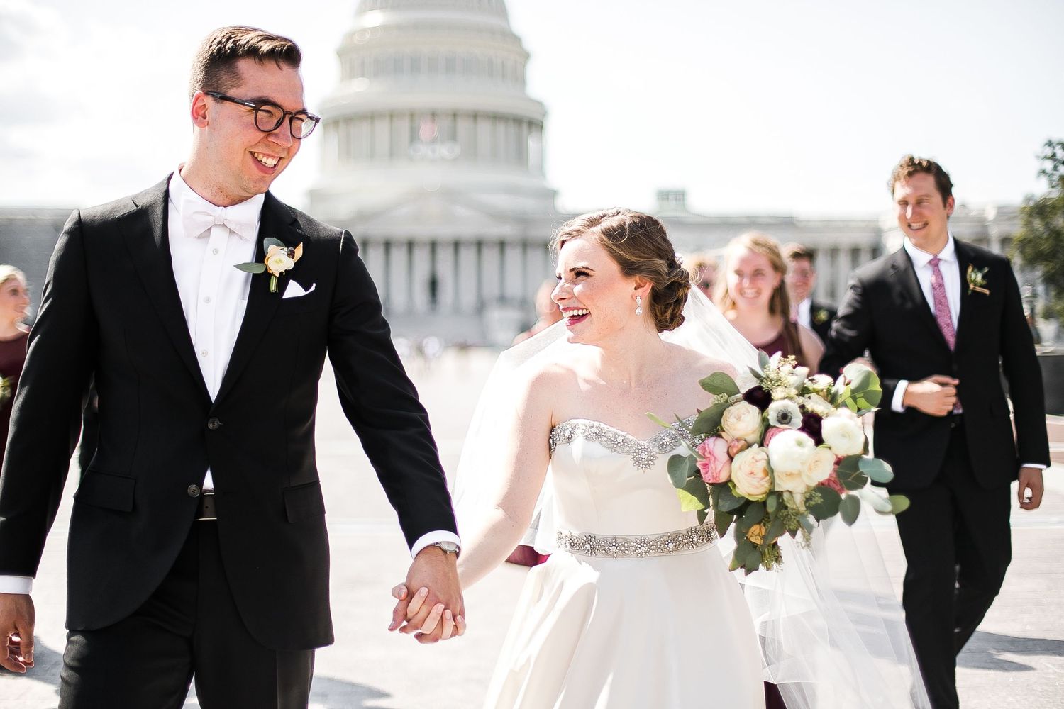 A joyful couple shares a candid moment holding hands in front of the US Capitol building on their wedding day.