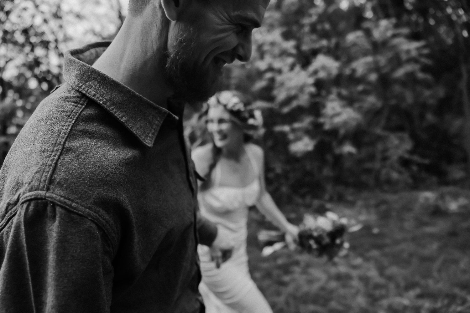 Black and white candid moment captured during an outdoor wedding celebration in nature.