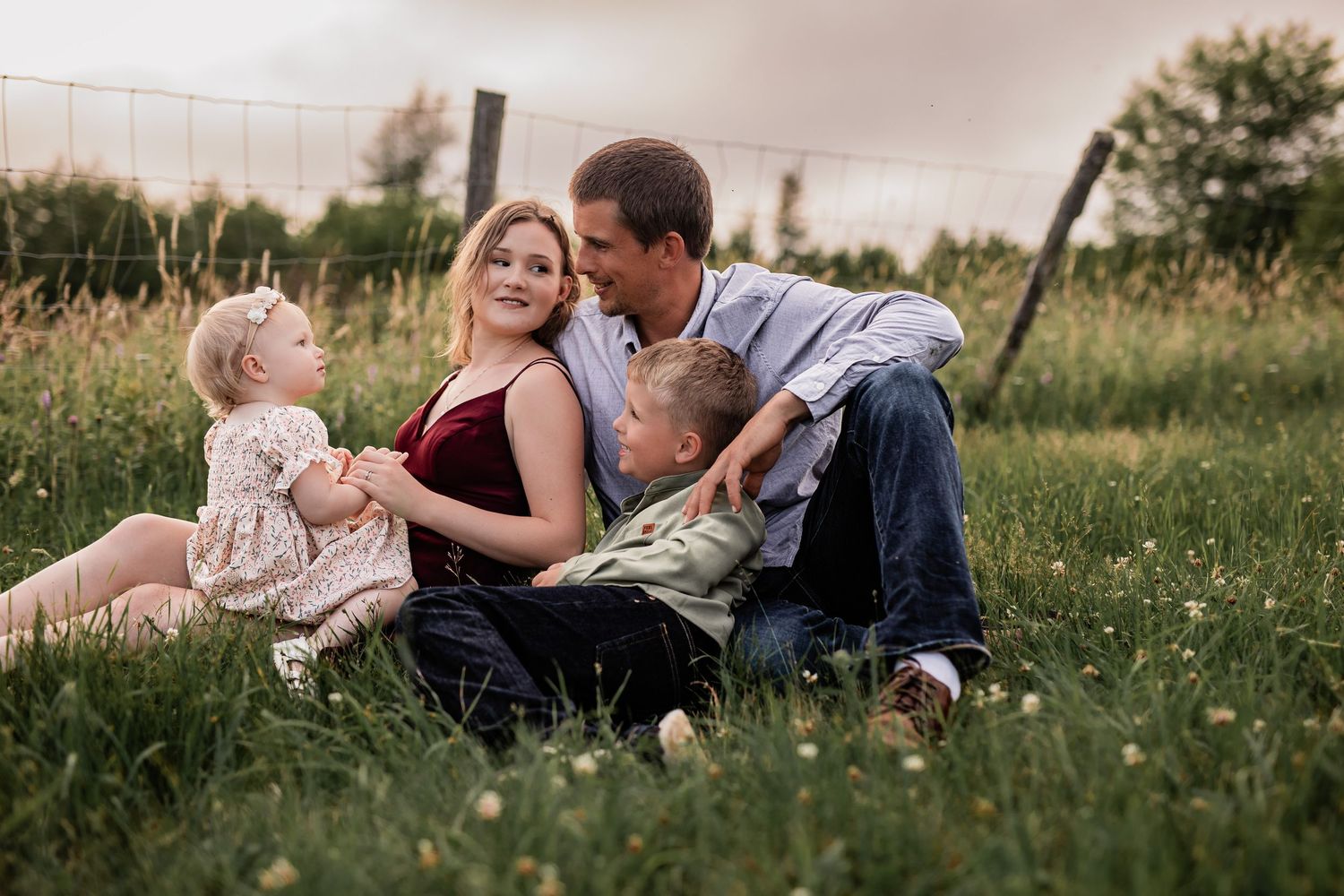 Candid family moments captured while lying in a grassy field at sunset.
