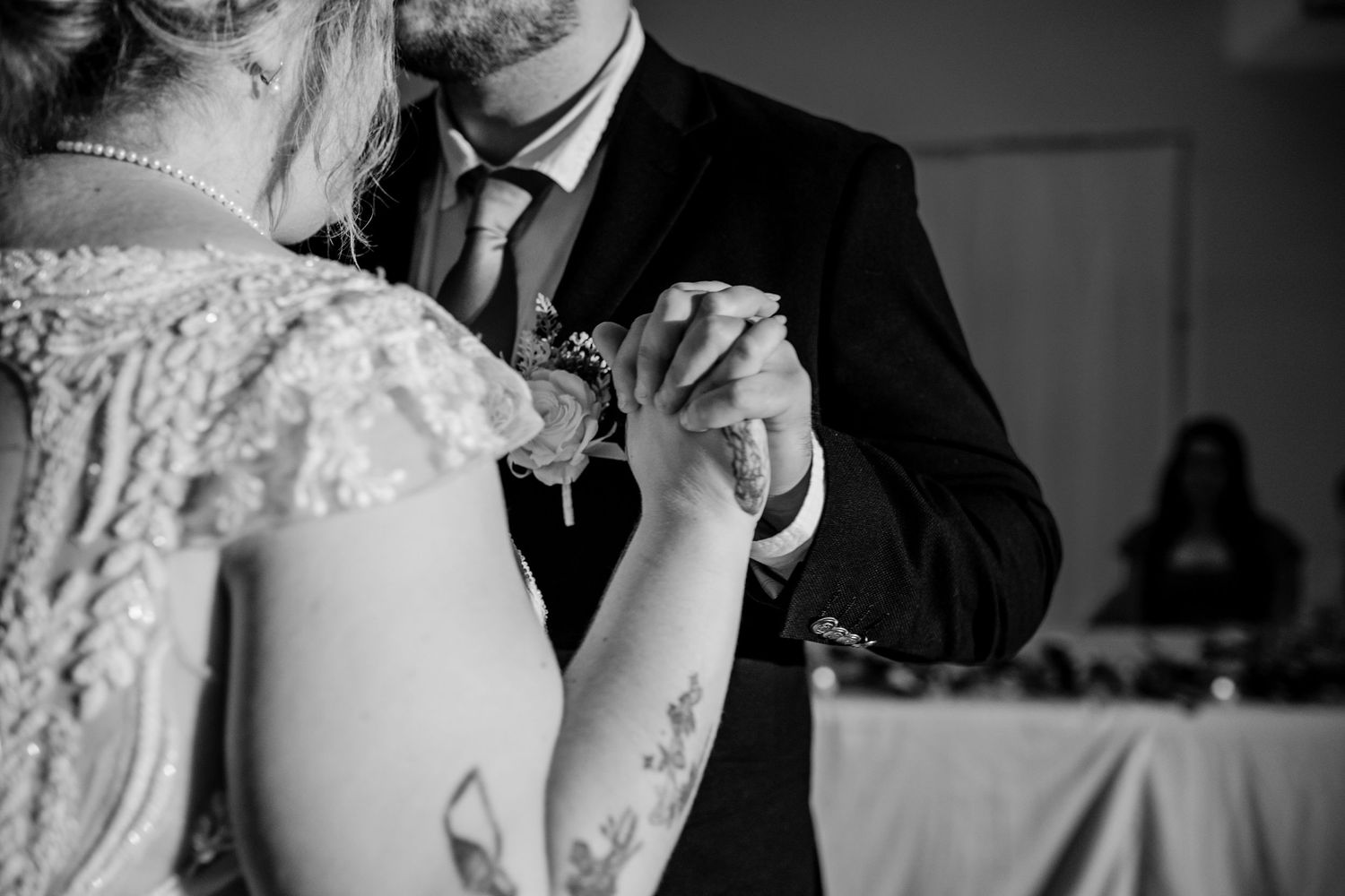 Close-up black and white photo of couple's hands during wedding dance.