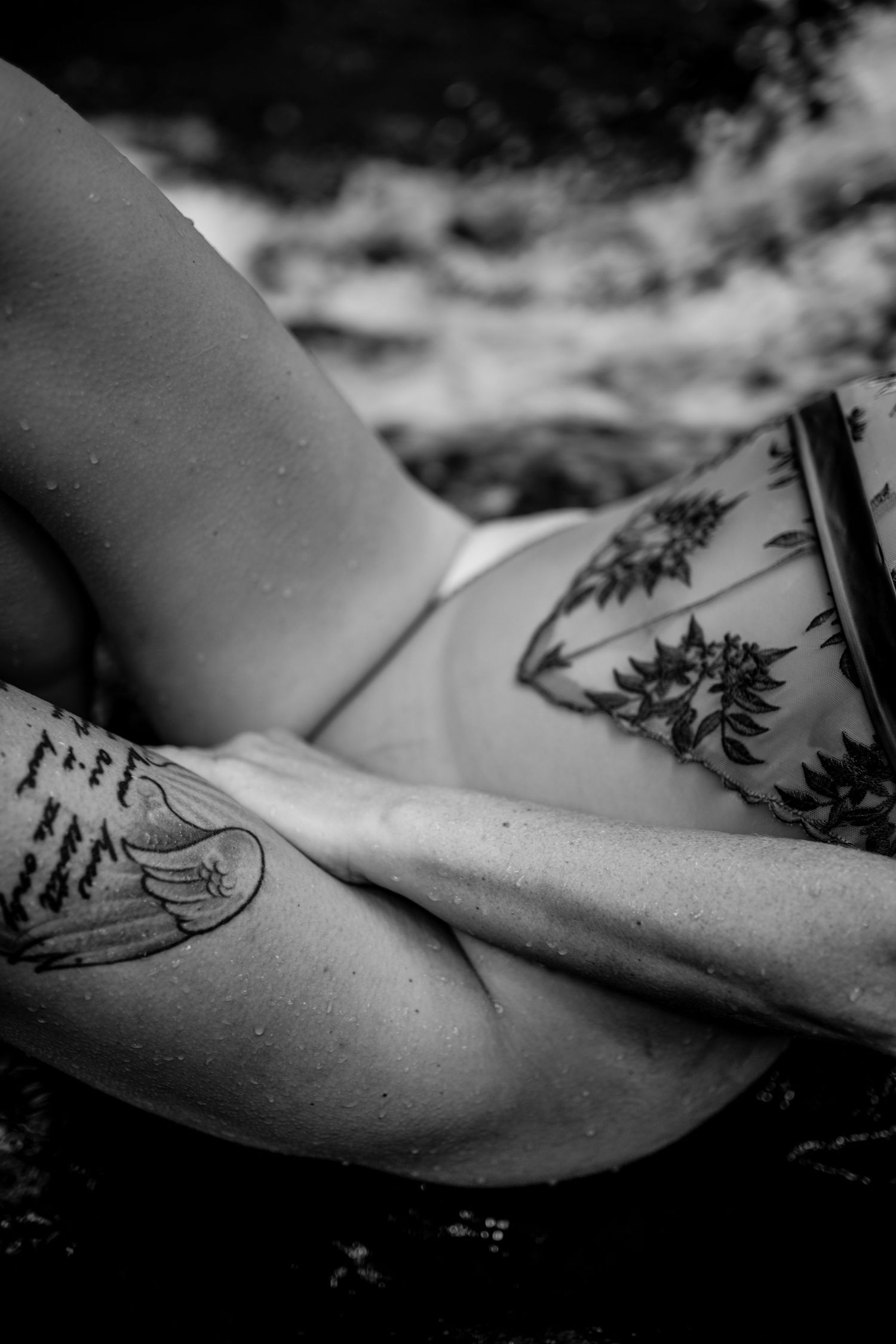 Black and white artistic photo of tattooed woman in patterned lingerie.