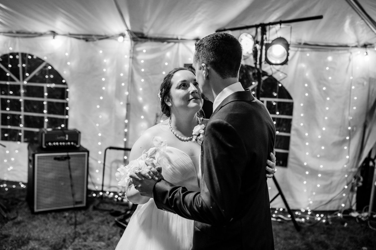 Wedding celebration inside a tent decorated with twinkling string lights creating a magical atmosphere.