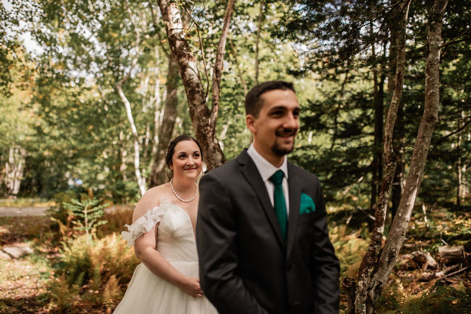 A wedding couple shares their first look moment in a wooded forest setting.