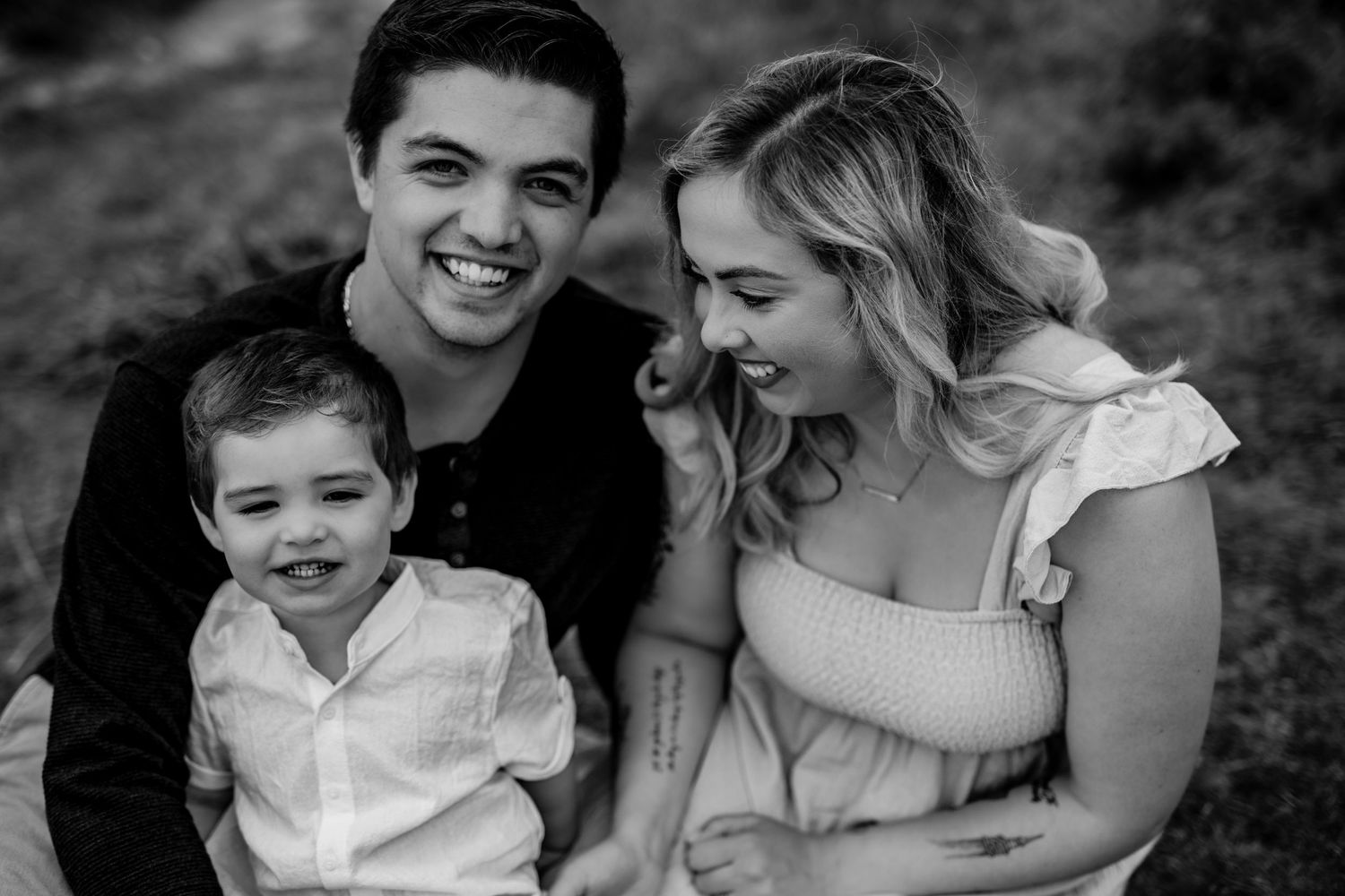 Black and white portrait of a family sharing joyful moment together outdoors.