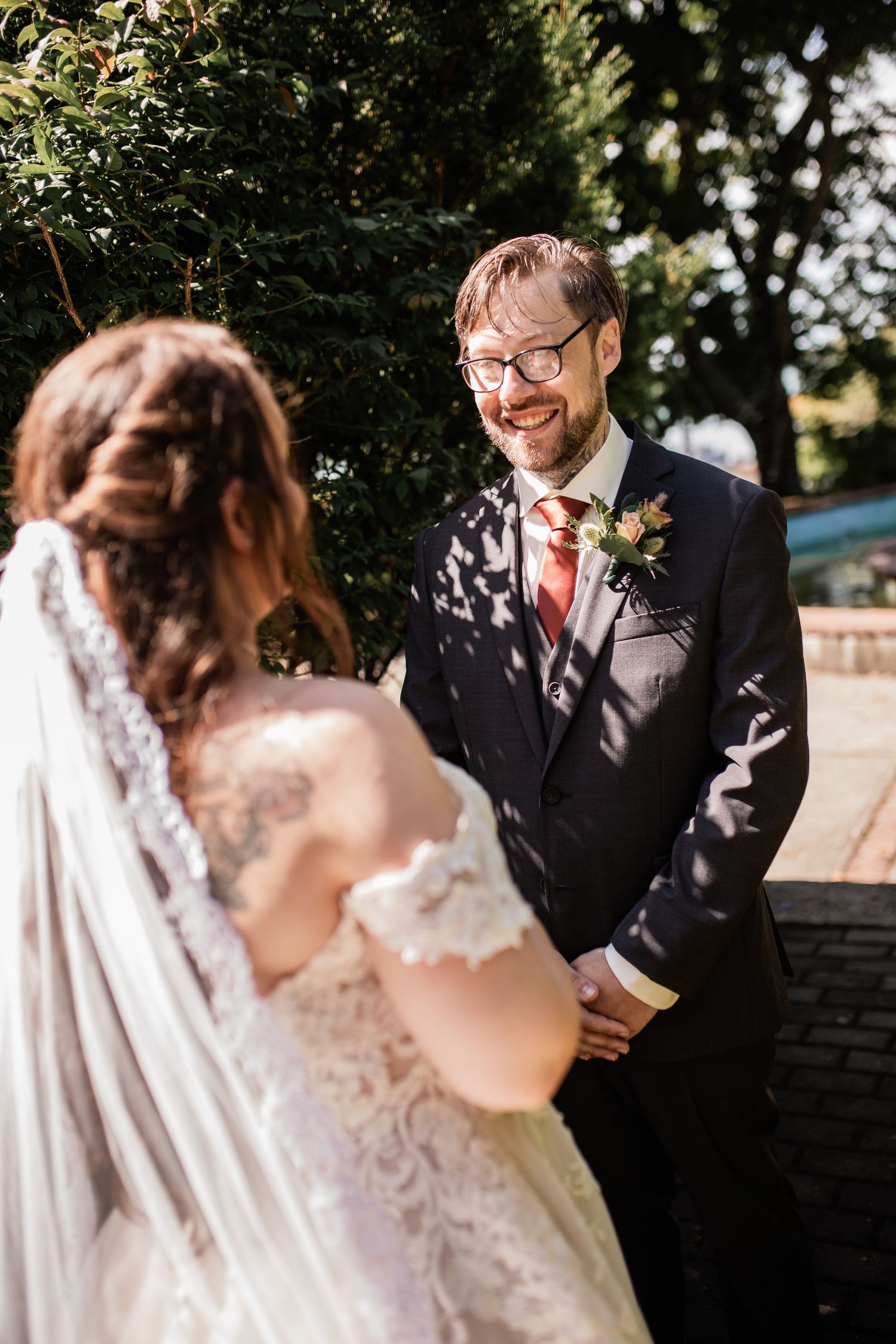 Wedding couple sharing intimate moment in dappled sunlight through trees.