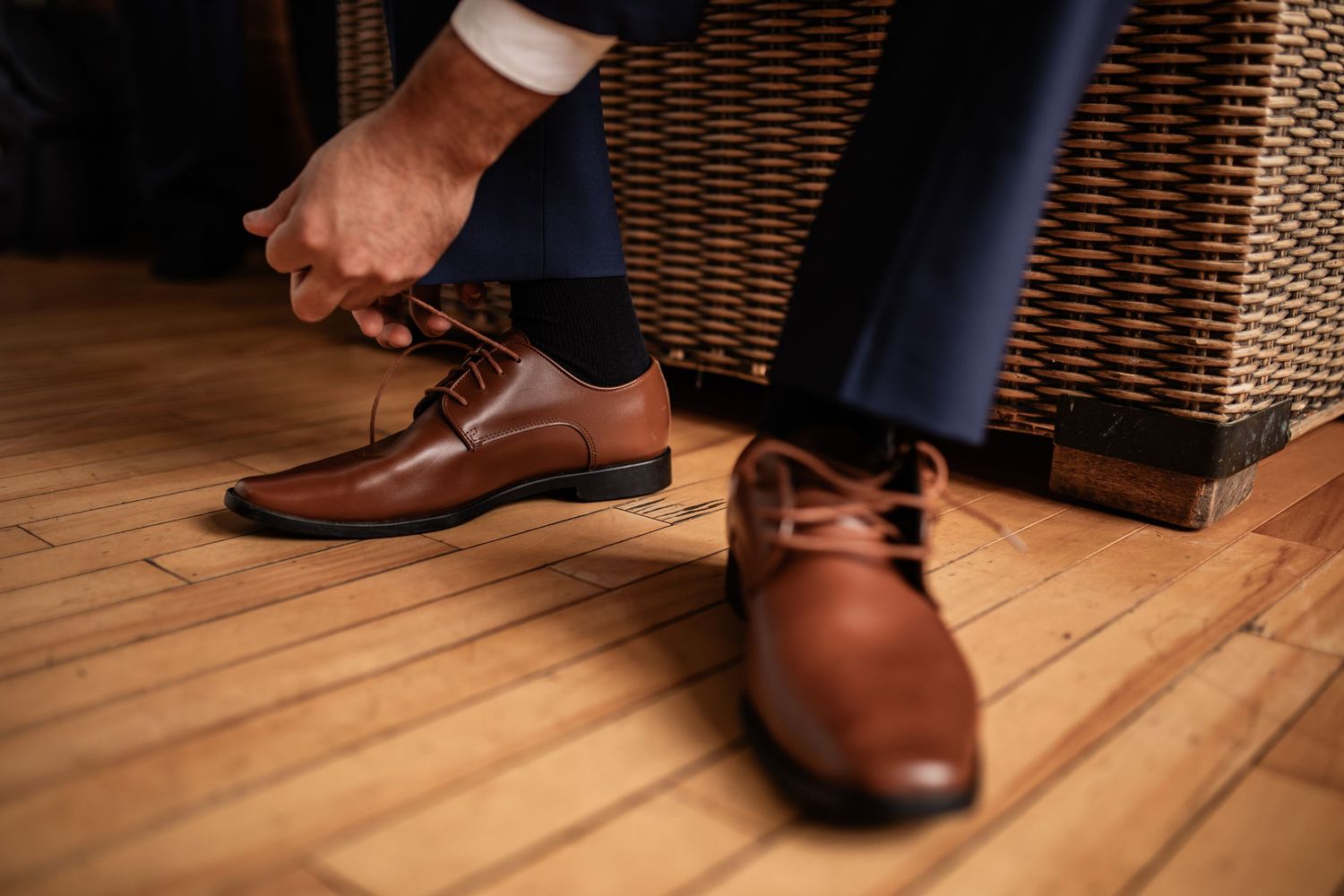 Detail shots of brown leather dress shoes on hardwood flooring.