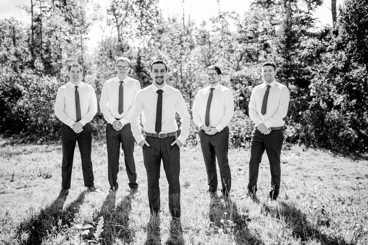 Group photo of five people in formal attire standing in a grassy outdoor setting.