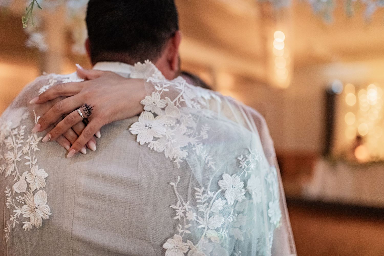 Close-up of hands embracing during a wedding dance, showing intricate lace detail on the dress.