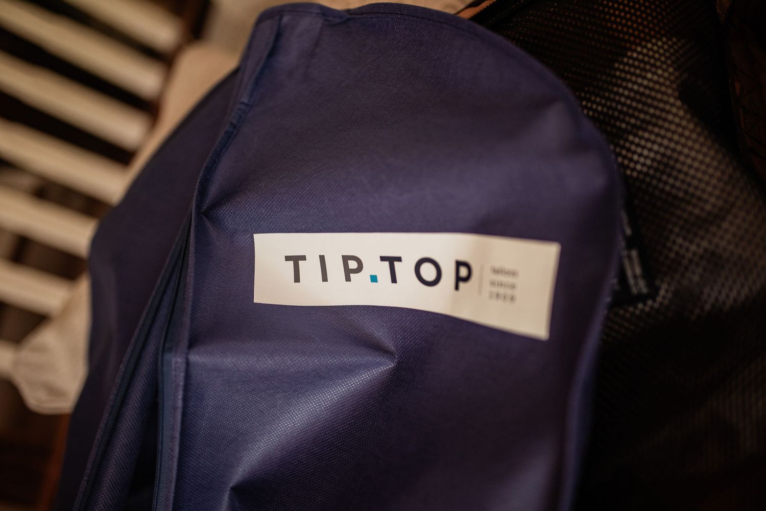 Close-up of a navy blue garment bag with TipTop branding label.