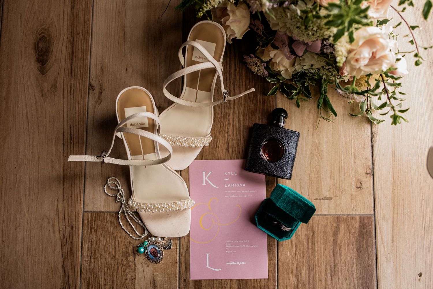 Wedding stationery and floral arrangements artfully arranged on wooden surface.