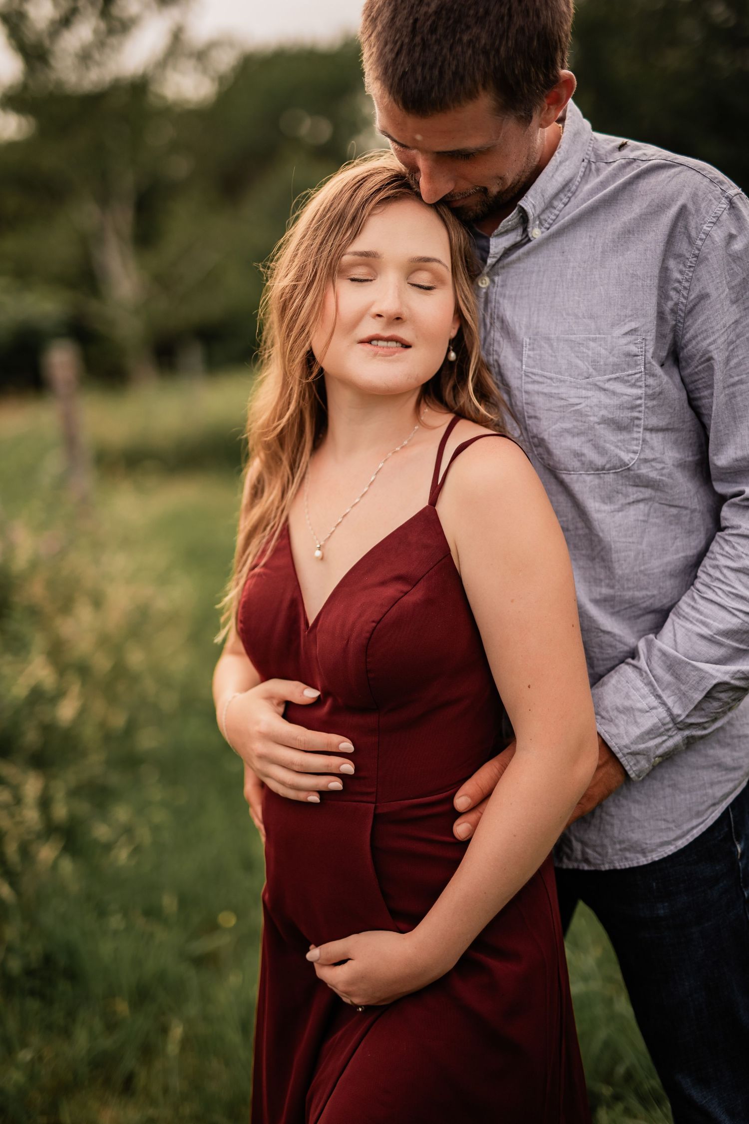 Intimate couple's portraits in burgundy and grey against a green natural backdrop.
