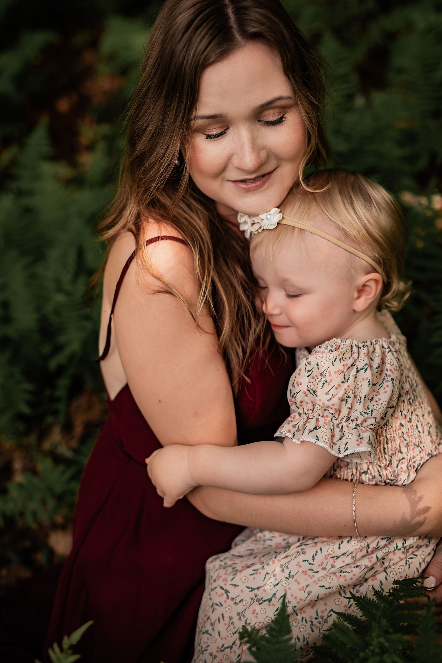 Gentle embrace between parent and young child surrounded by greenery.