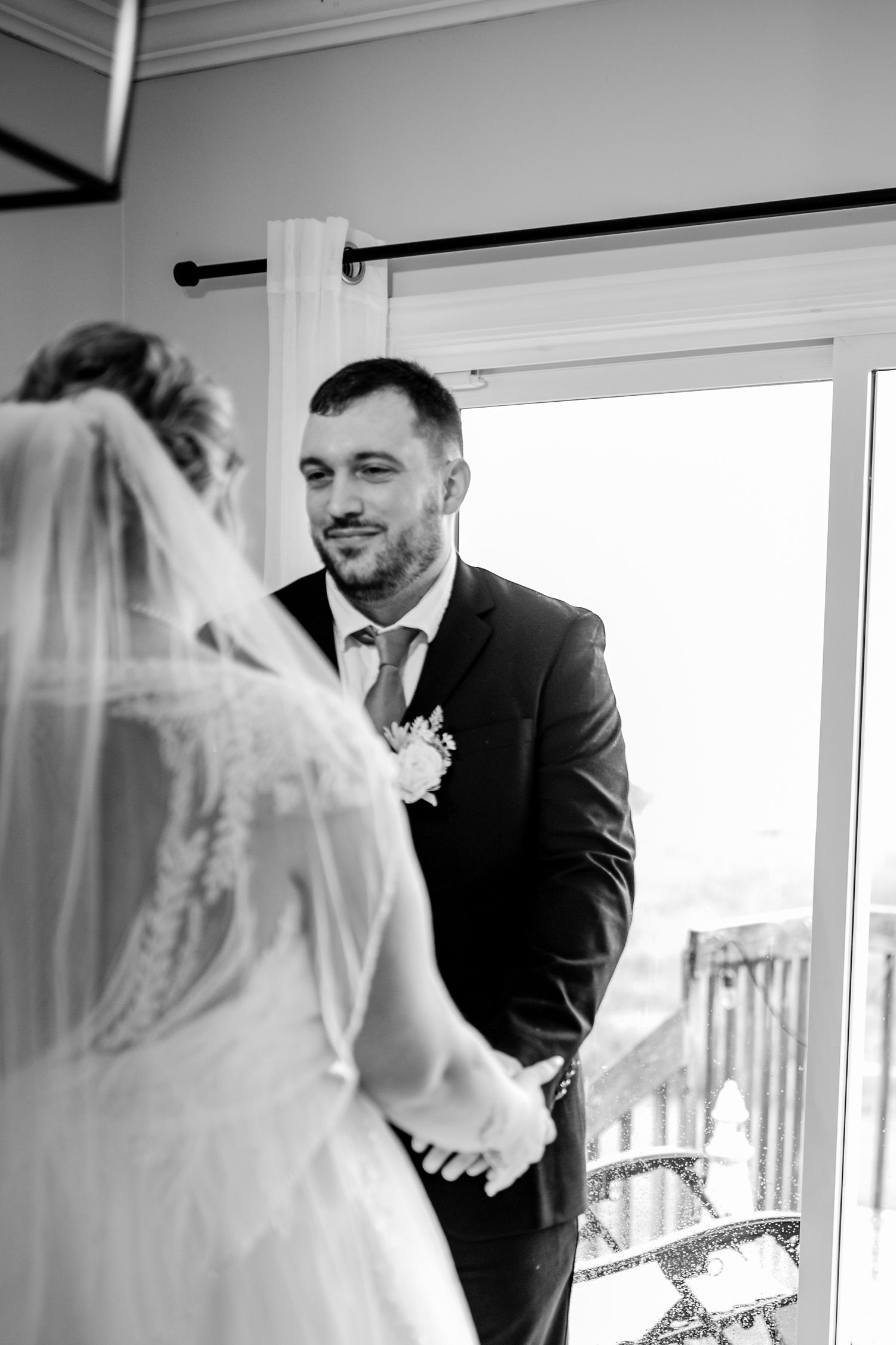 Black and white wedding photo showing an intimate moment by a window.