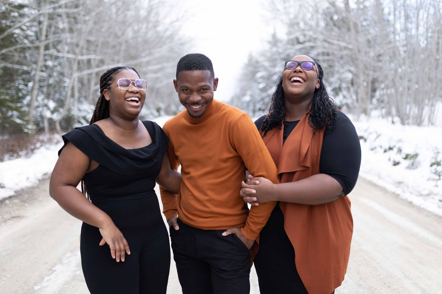 Three people sharing laughter together on a snowy winter road.