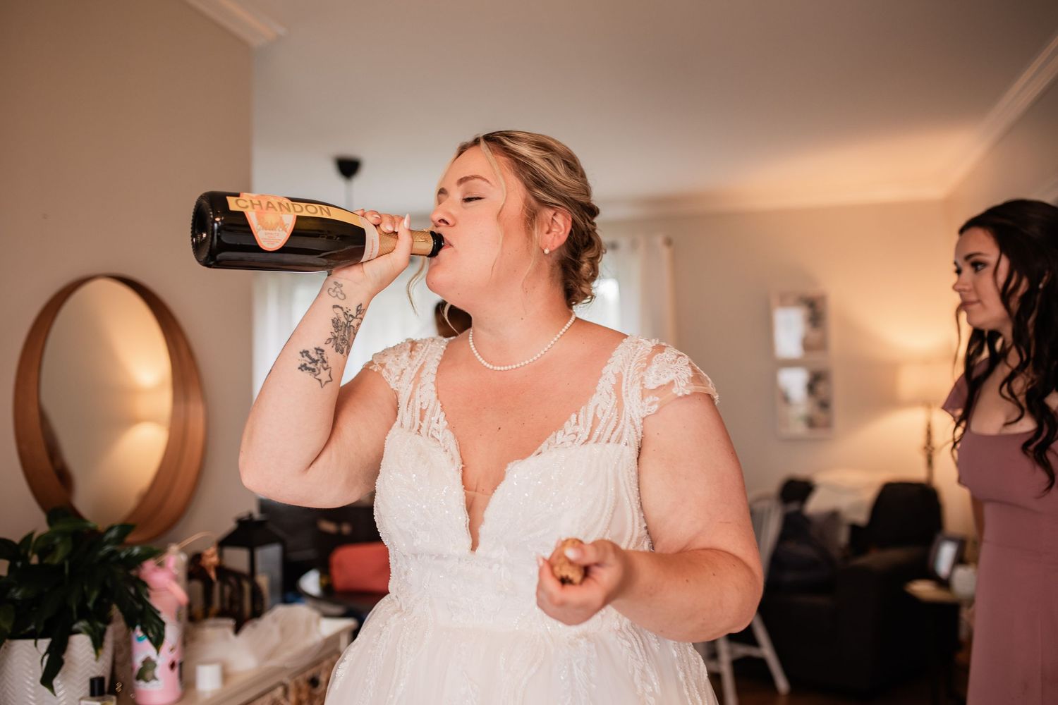 A celebratory moment as someone in a wedding dress drinks from a champagne bottle.