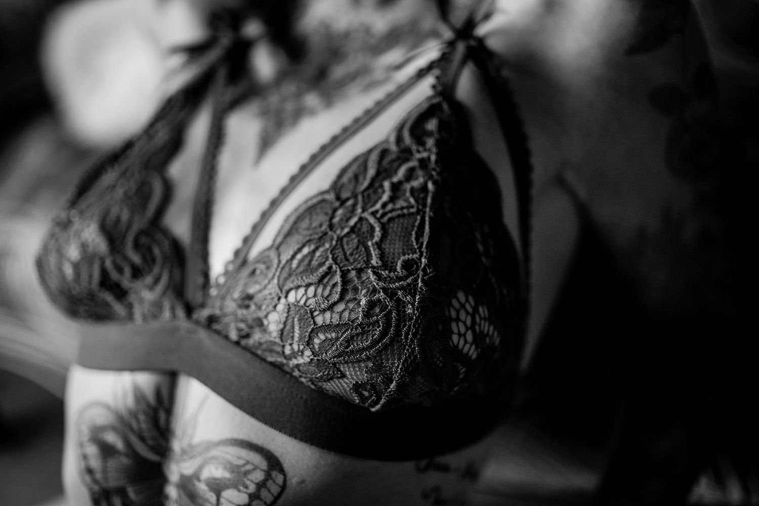 Close up black and white photo of a lace bralette with delicate floral details.