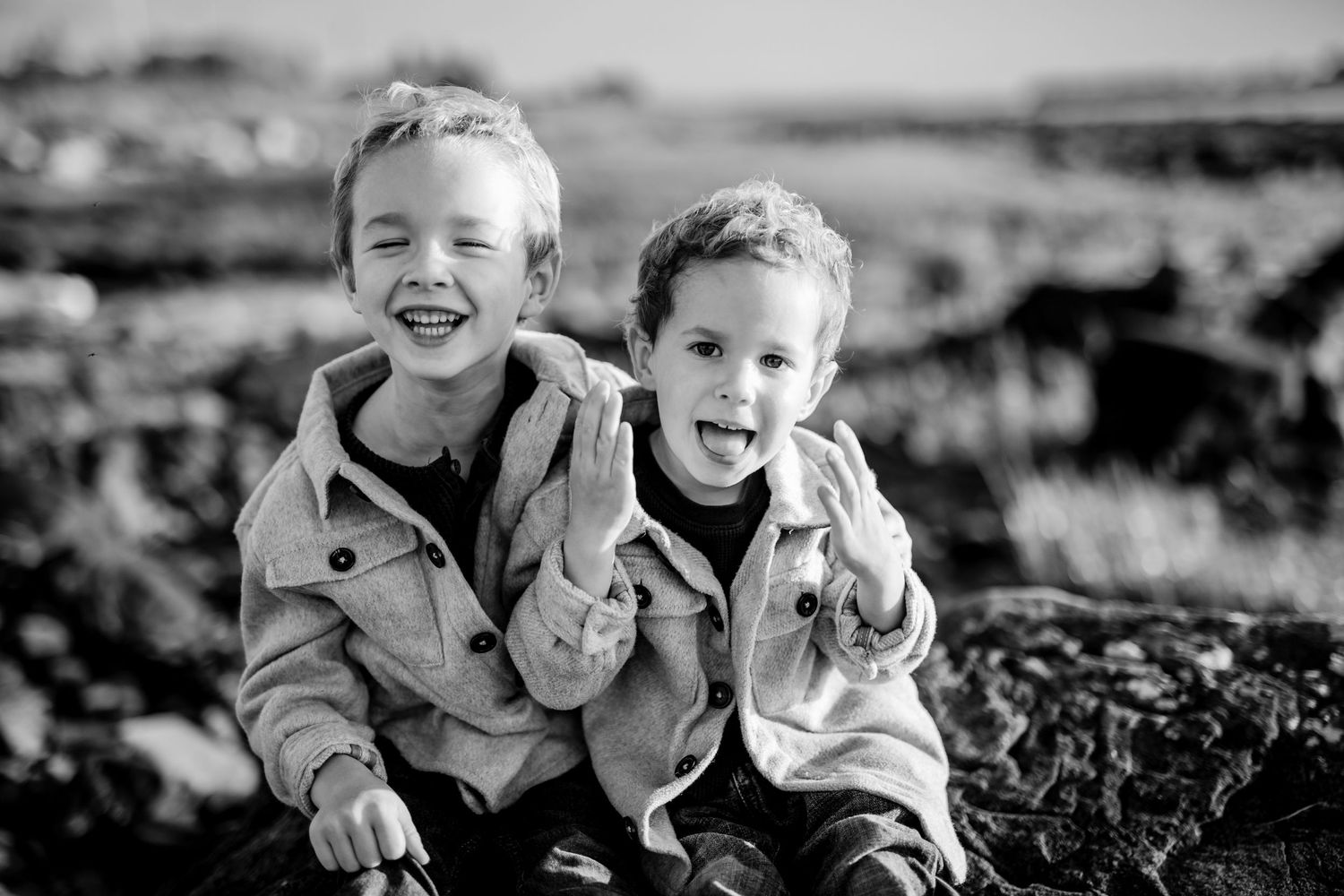 Black and white portrait of children laughing together against a natural background.