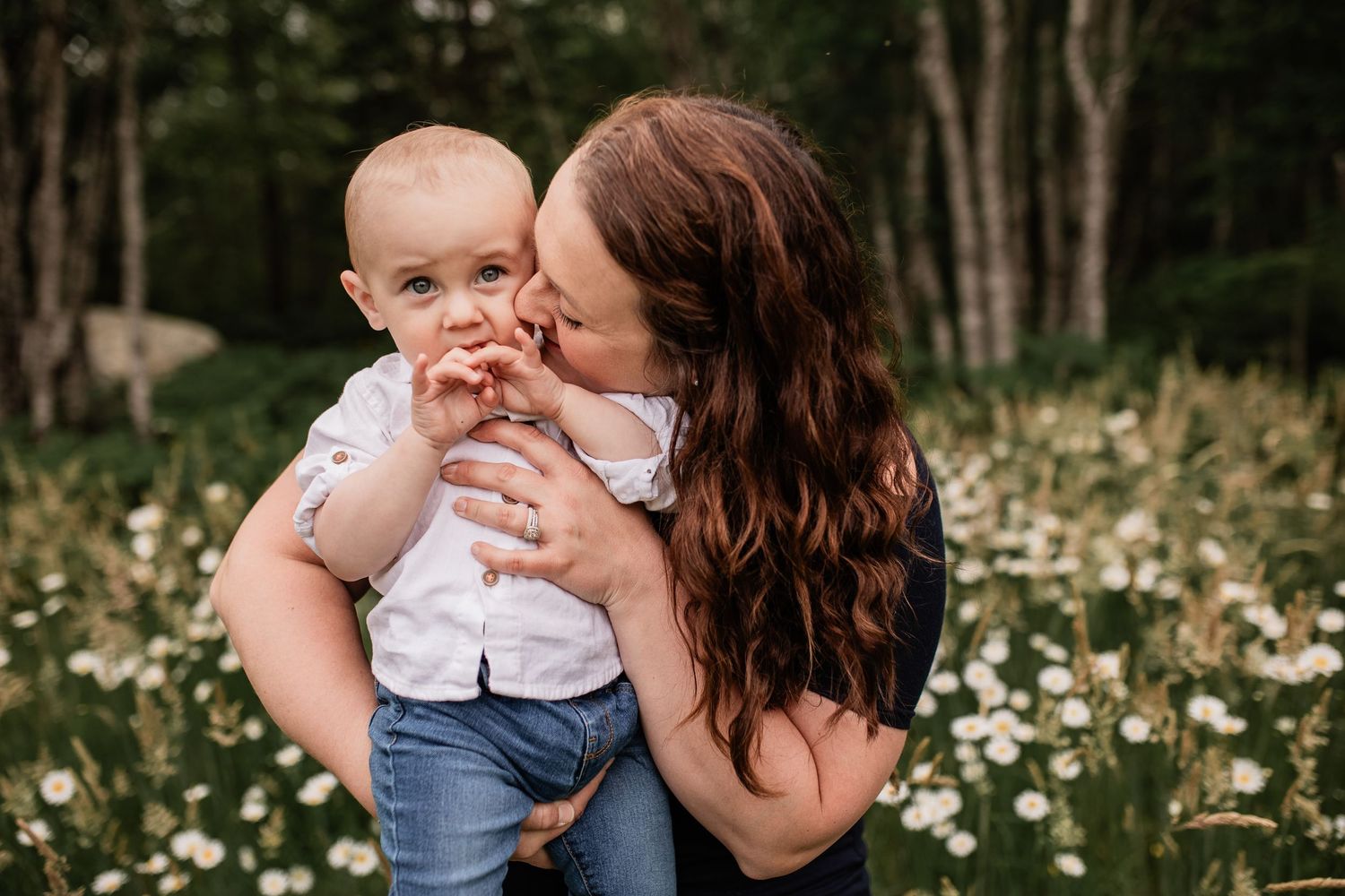 Mother and baby share tender moment in field of wildflowers.