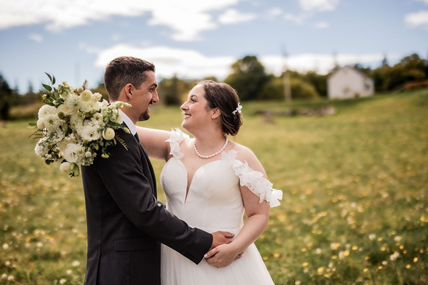 Romantic wedding portrait in a meadow with white floral bouquet.