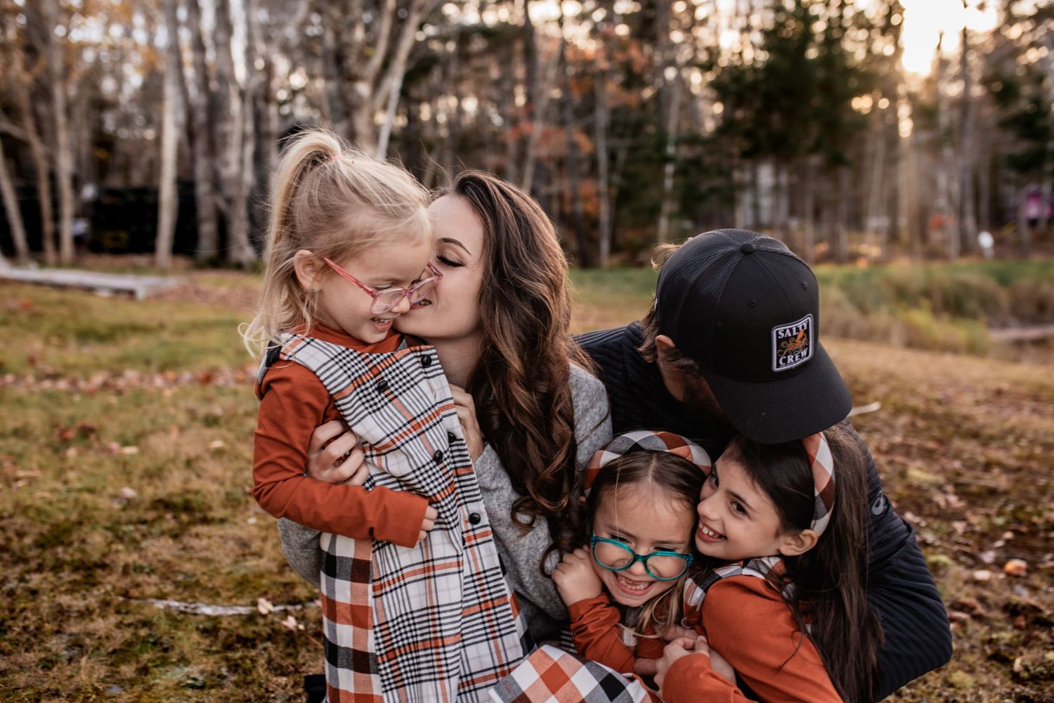 Intimate family moment captured in warm autumn light with everyone wearing coordinating plaid shirts.