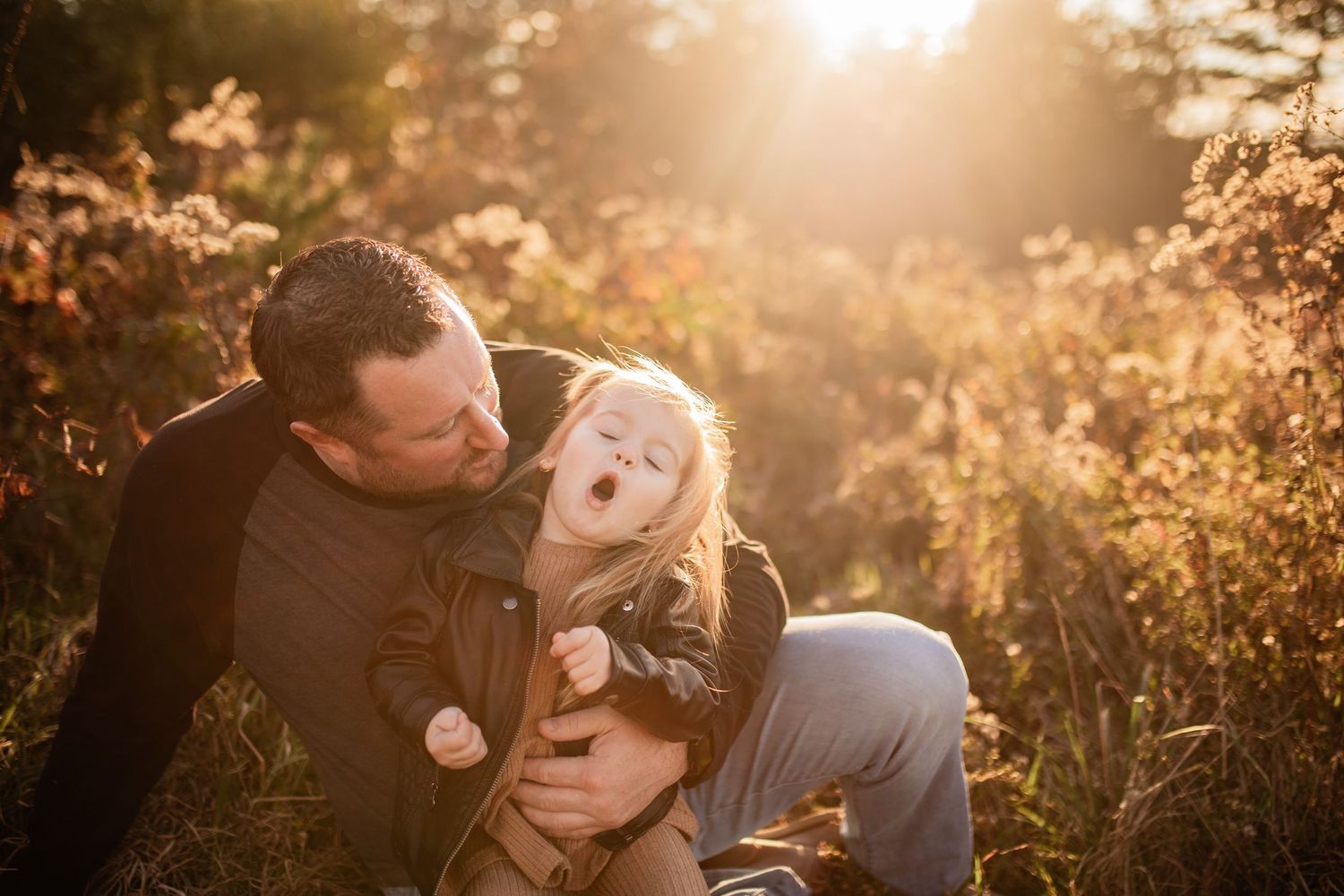 A heartwarming sunset portrait of two people sharing a joyful moment in tall grass.